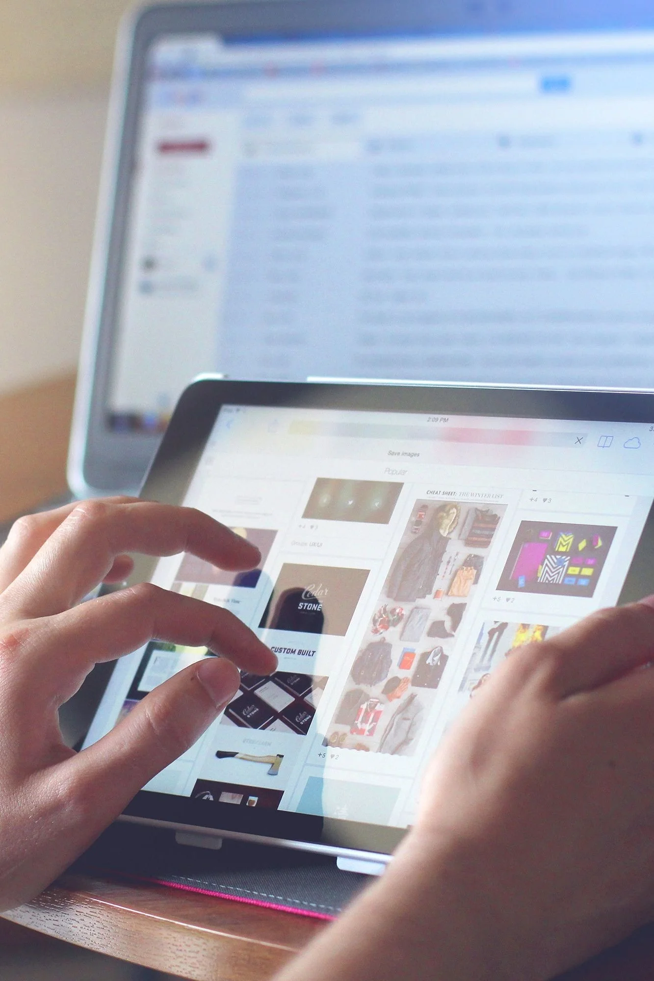 Person looks at tablet and computer at the same time, getting things organized.