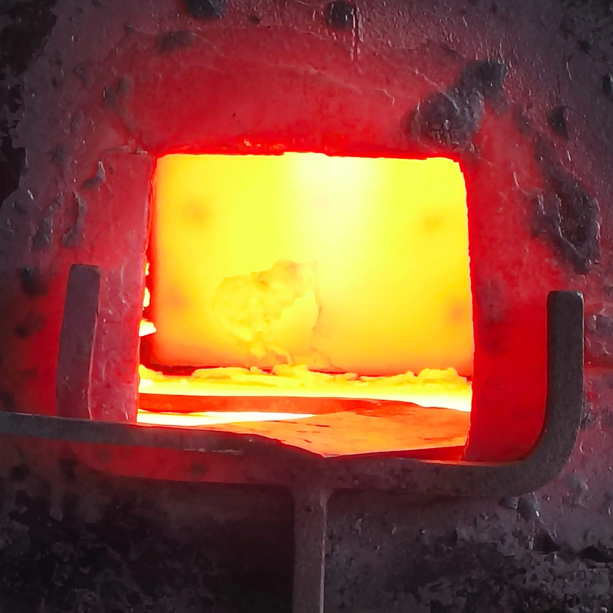 A glowing rectangular light source emitting a yellow light, surrounded by black and red rocks or volcanic material.