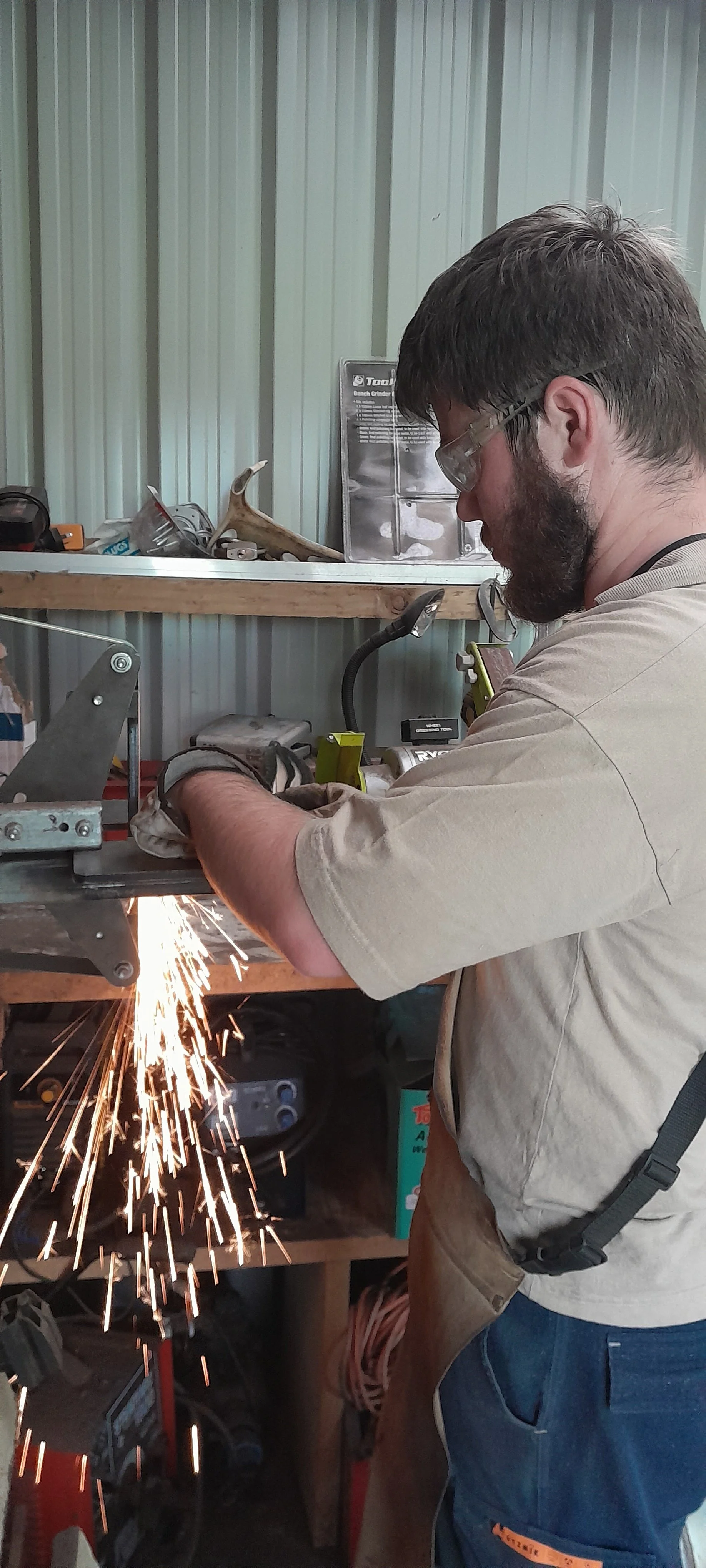 Man wearing safety glasses cutting metal with a power saw sparks flying.