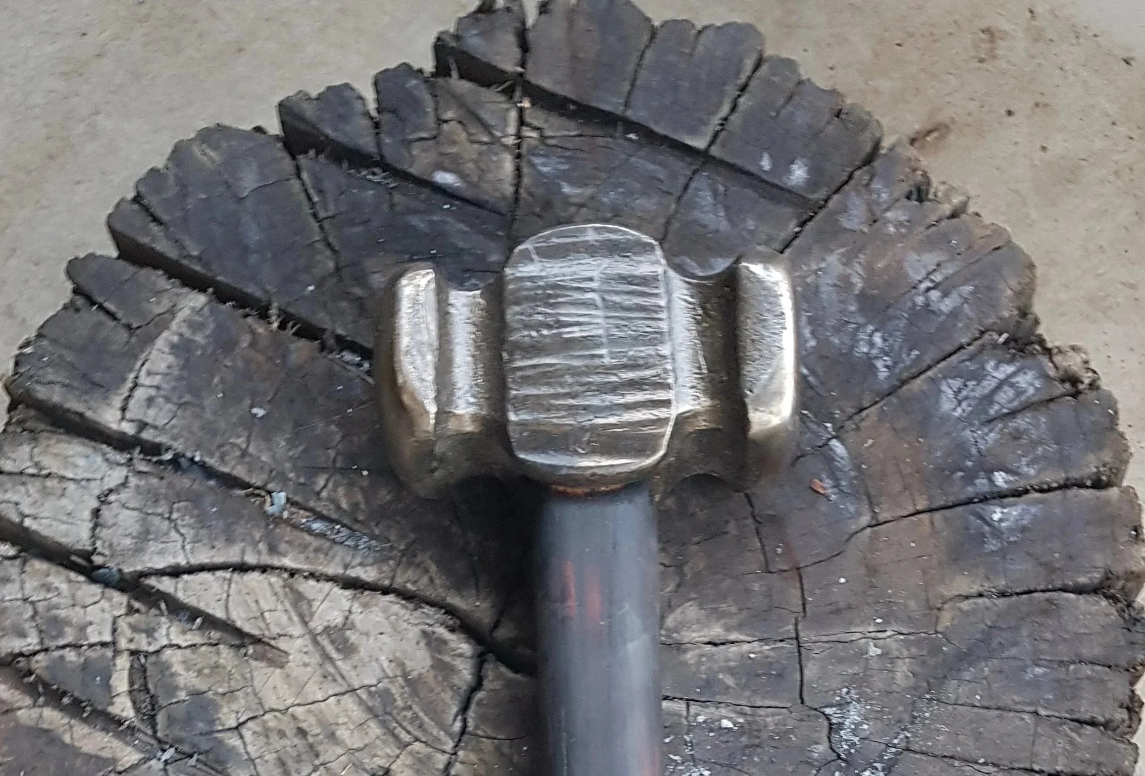 A metal object pressed into a piece of charred wood and dirt on the ground.