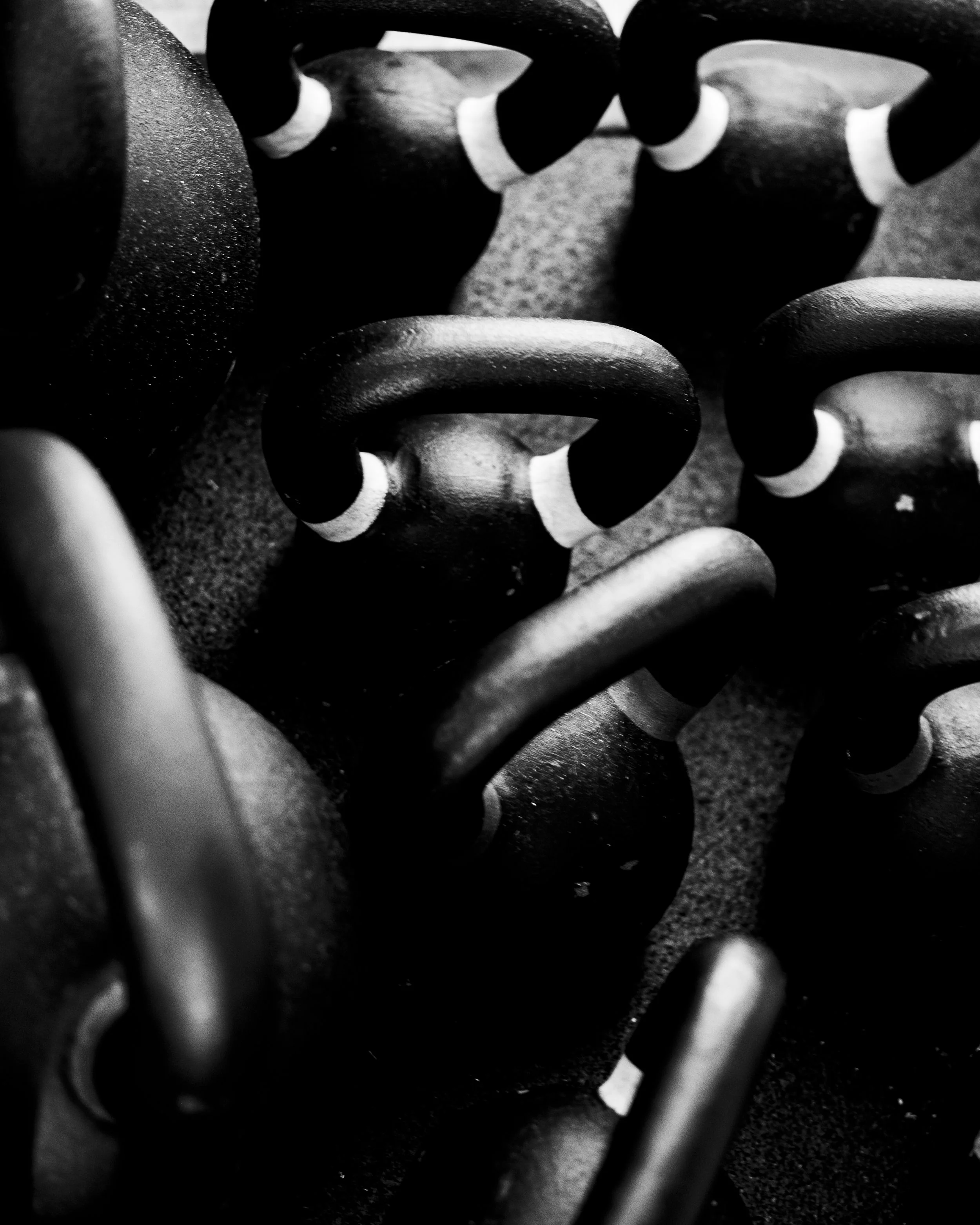 Close-up of black and white kettlebells arranged on a floor, shot in black and white.
