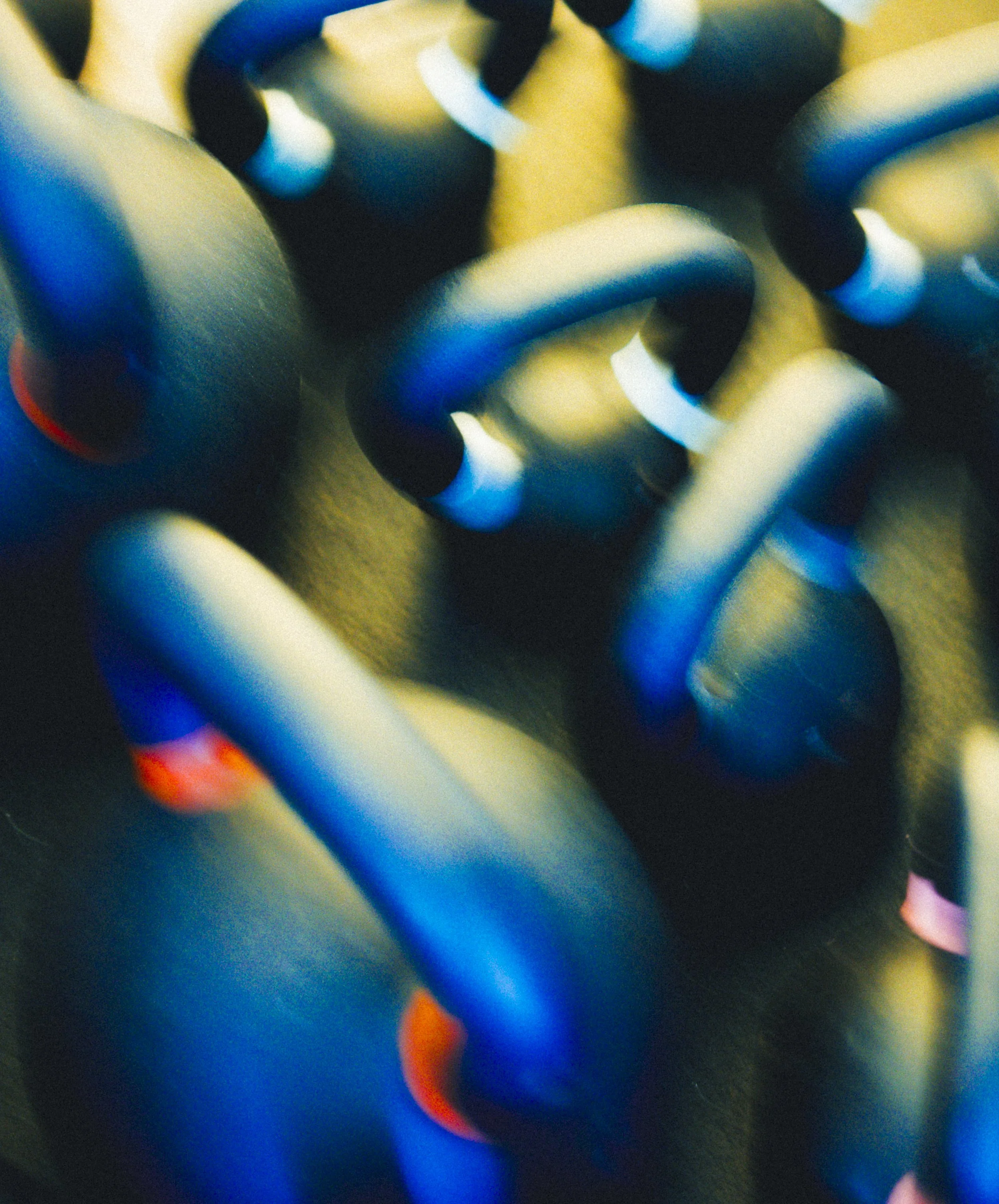 Close-up photo of a colorful chain, showing interconnected black, white, yellow, orange, blue, and red links, with a blurred background.