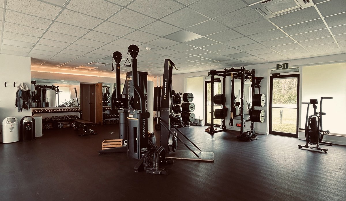 Empty gym with weightlifting equipment, cardio machines, and free weights.