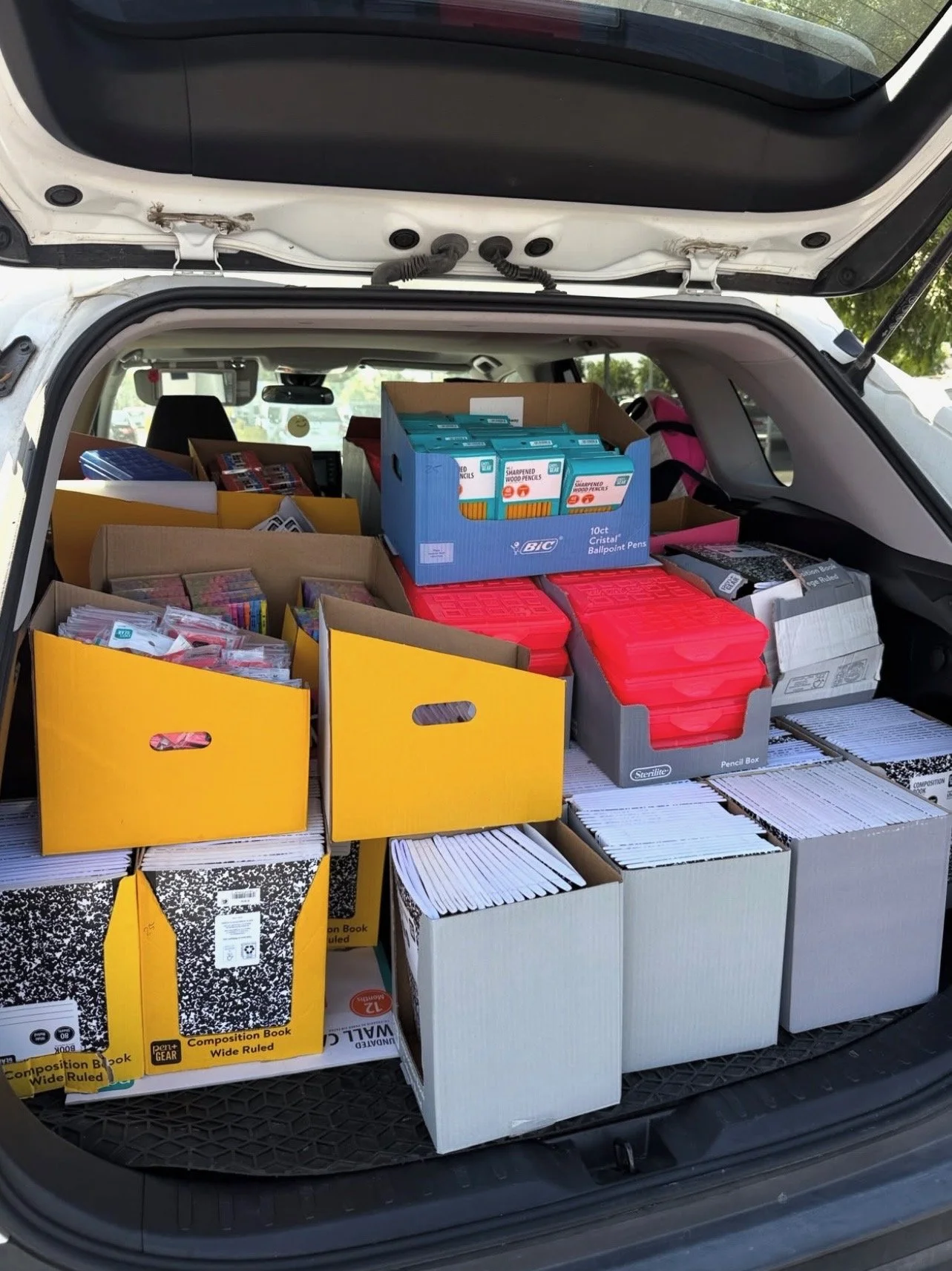 Back of a vehicle packed with school supplies, including notebooks, pencils, and boxes of supplies.