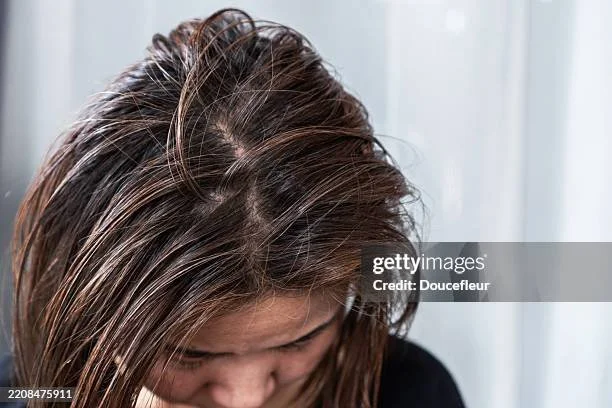 Close-up of a woman with dark brown hair looking down.