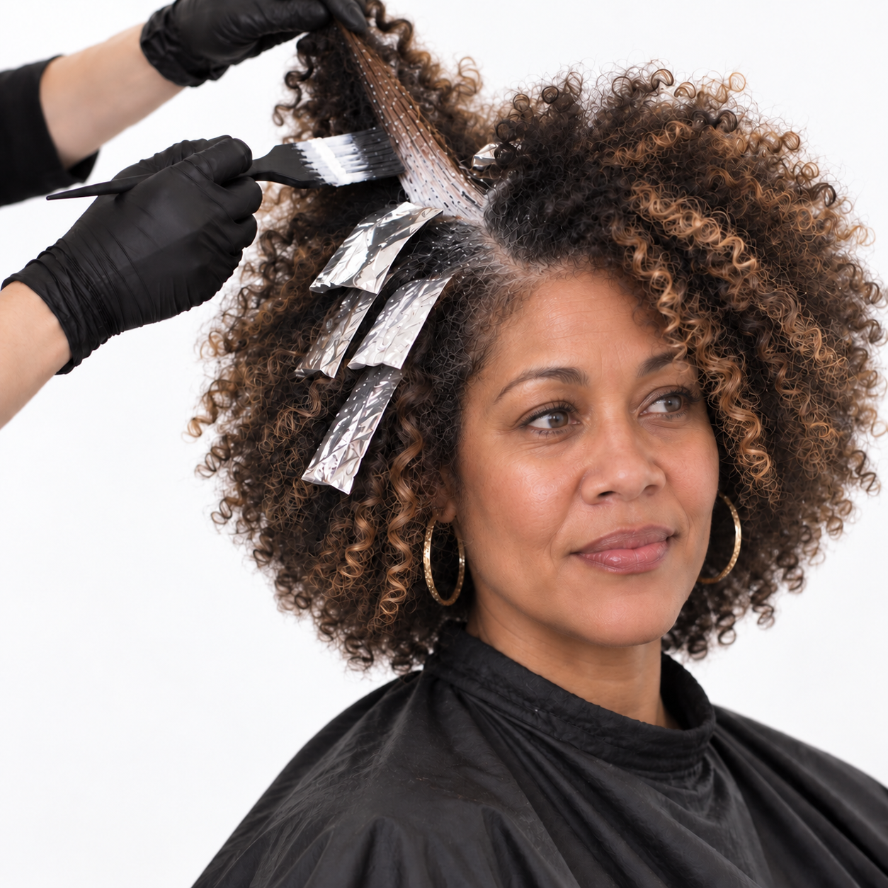 Woman getting her hair colored in a salon with foil highlights and aluminum foil strips.