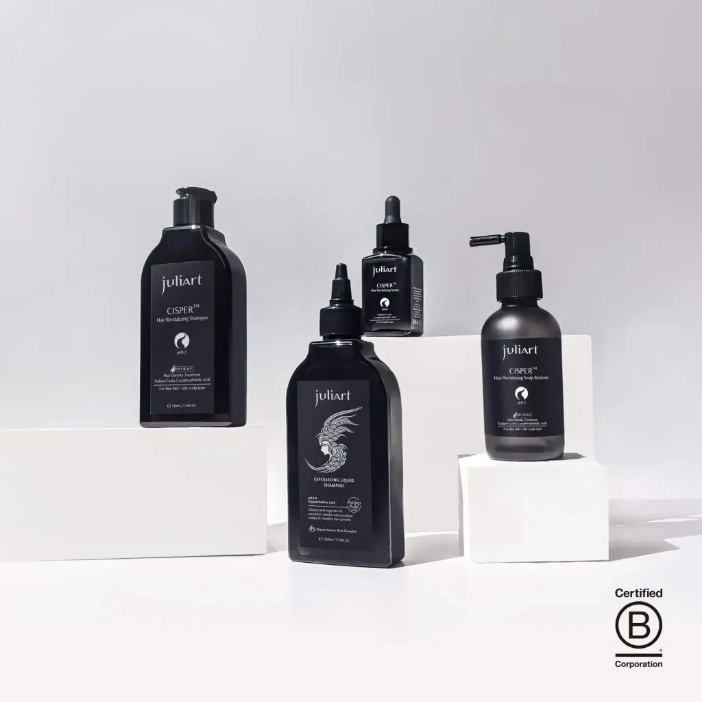 Collection of black hair care bottles, including shampoo and scalp renewer, displayed on white platforms against a light background.