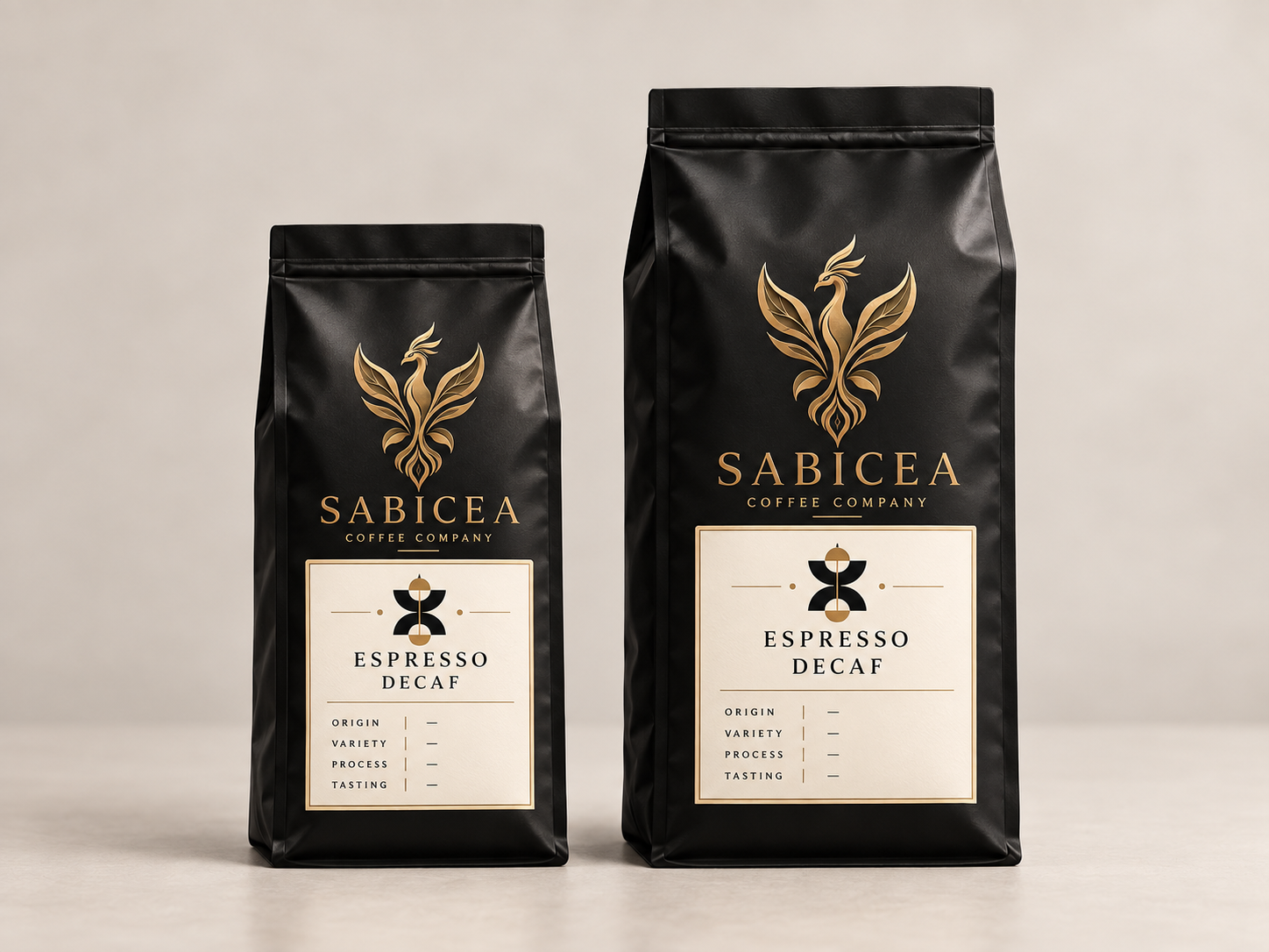 Two black coffee bags from Sabicea Coffee Company, labeled as Espresso Decaf, with gold and black branding, placed on a neutral background.