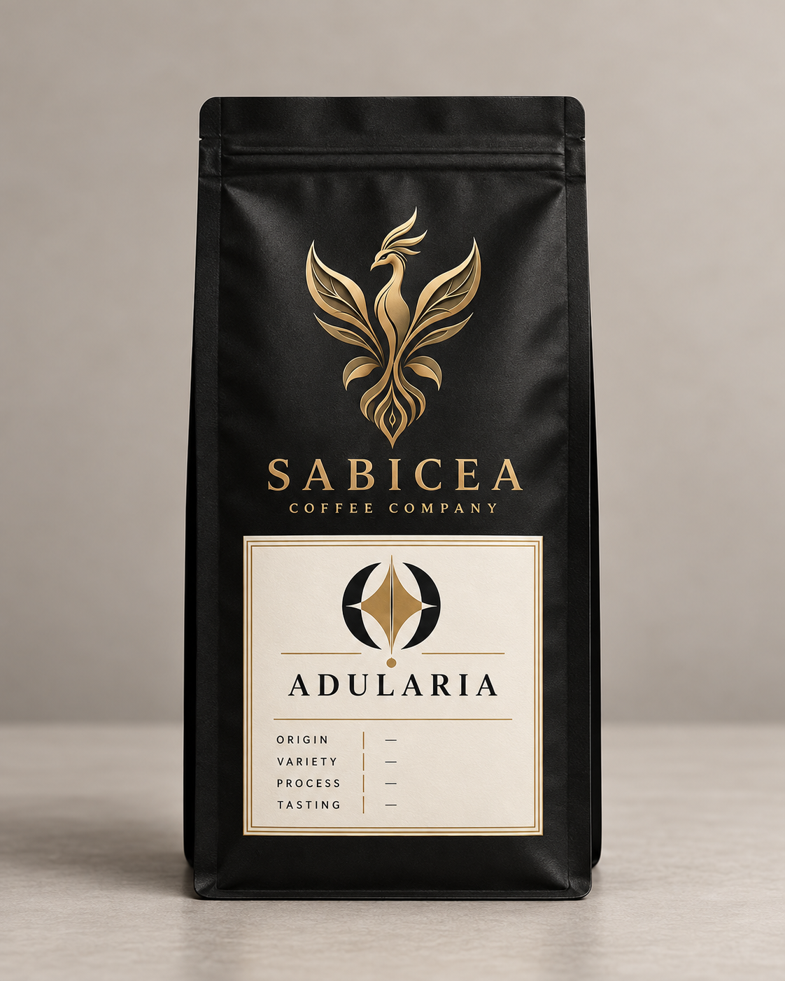 A black coffee bag with gold and white label from Sabicea Coffee Company, featuring a stylized phoenix logo and the name Adularia.