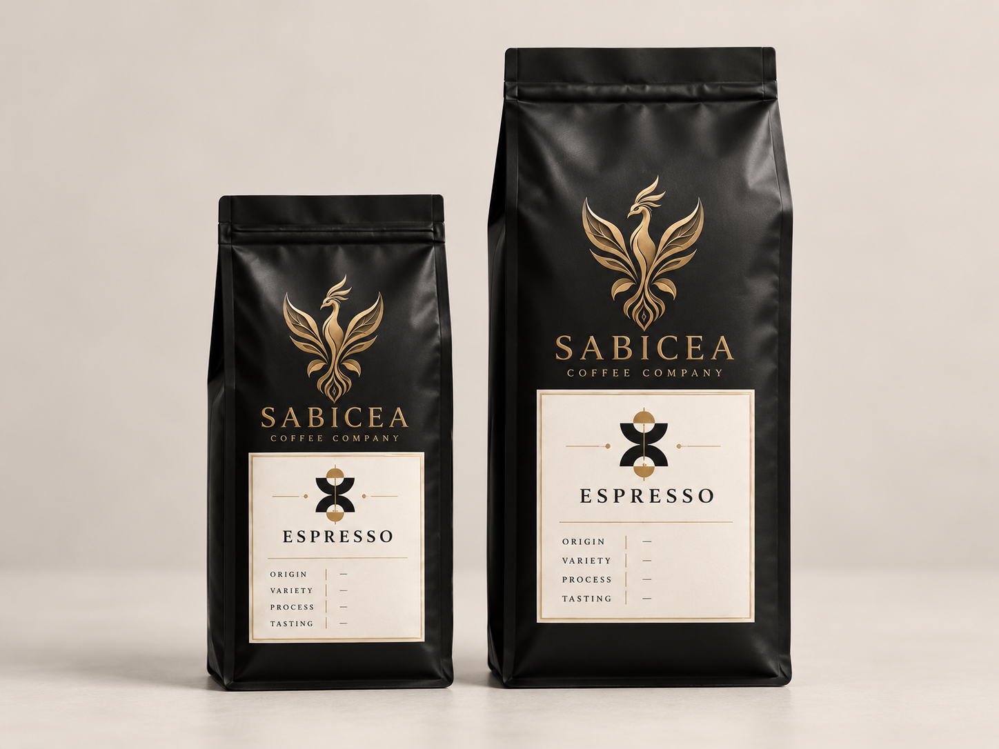 Two black bags of Sabicea Coffee Company espresso with gold and white labels, featuring a stylized bird logo, on a plain background.