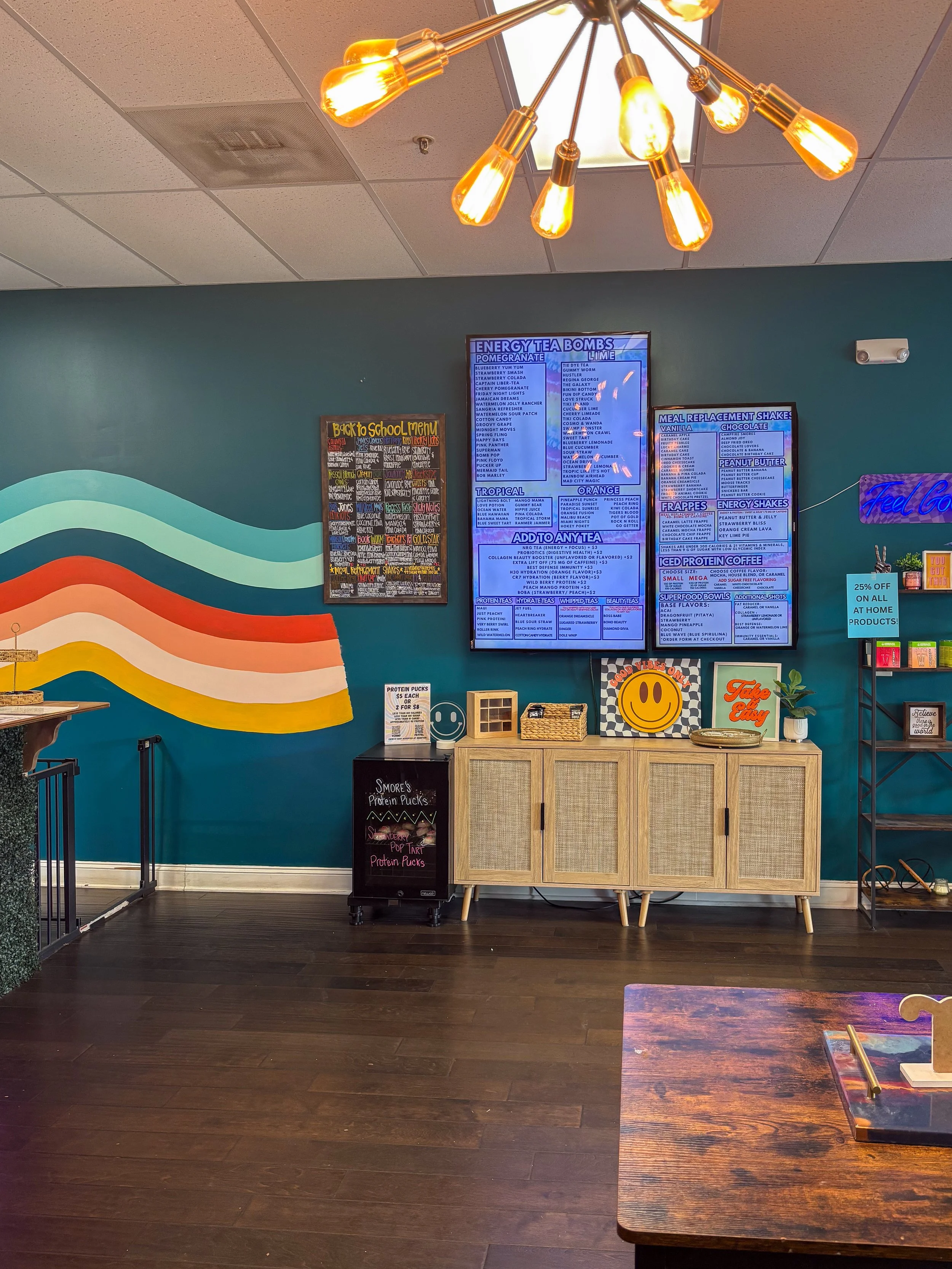 Wide interior with rainbow mural + menu boards + chandelier