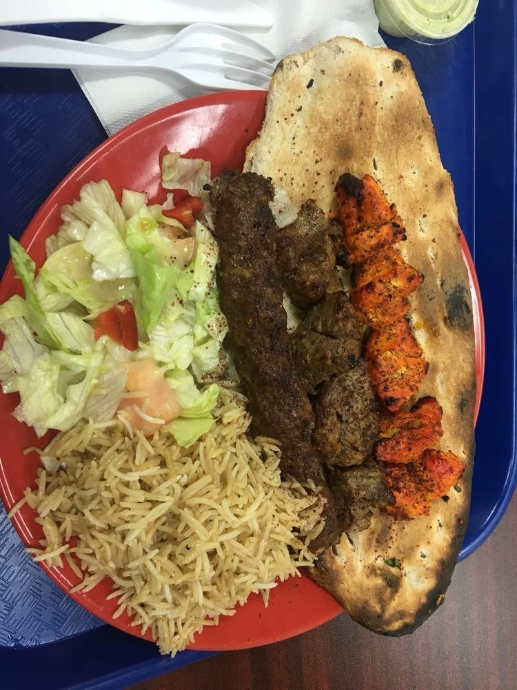 Plate of Middle Eastern food with grilled meat, rice, salad, and flatbread