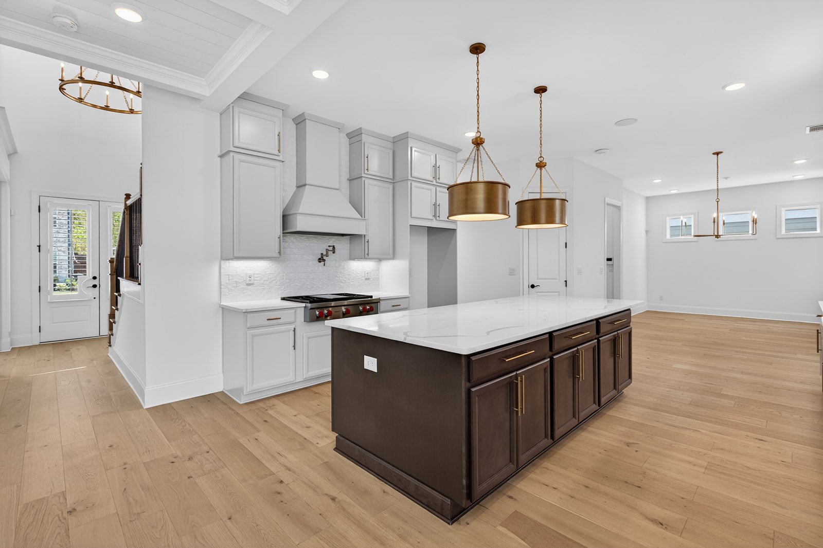 Modern kitchen with white cabinets, a dark wood island with a white marble countertop, and gold pendant lights.
