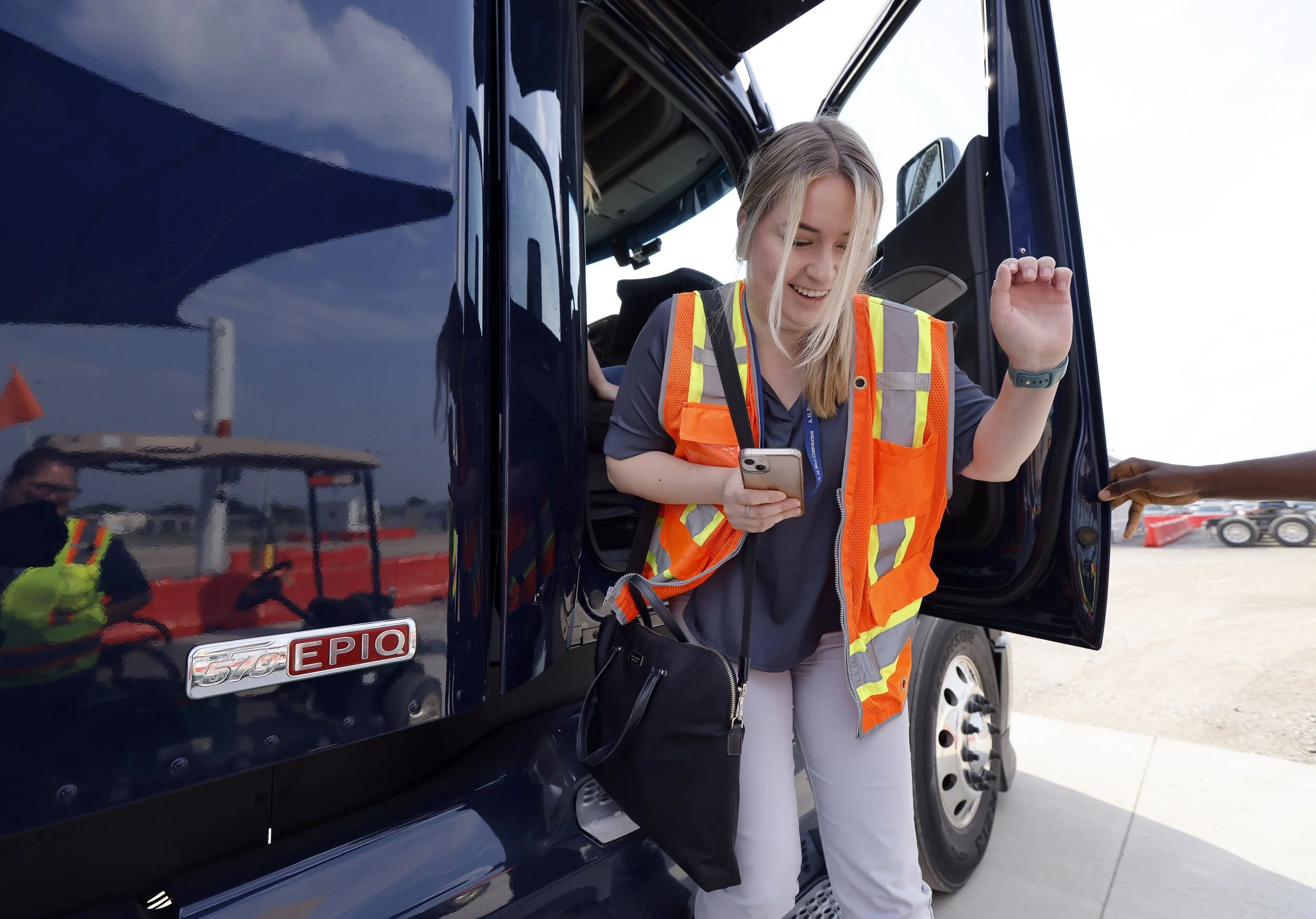 Alexandra Skores in an orange safety vest coming out of a large autonomous truck.