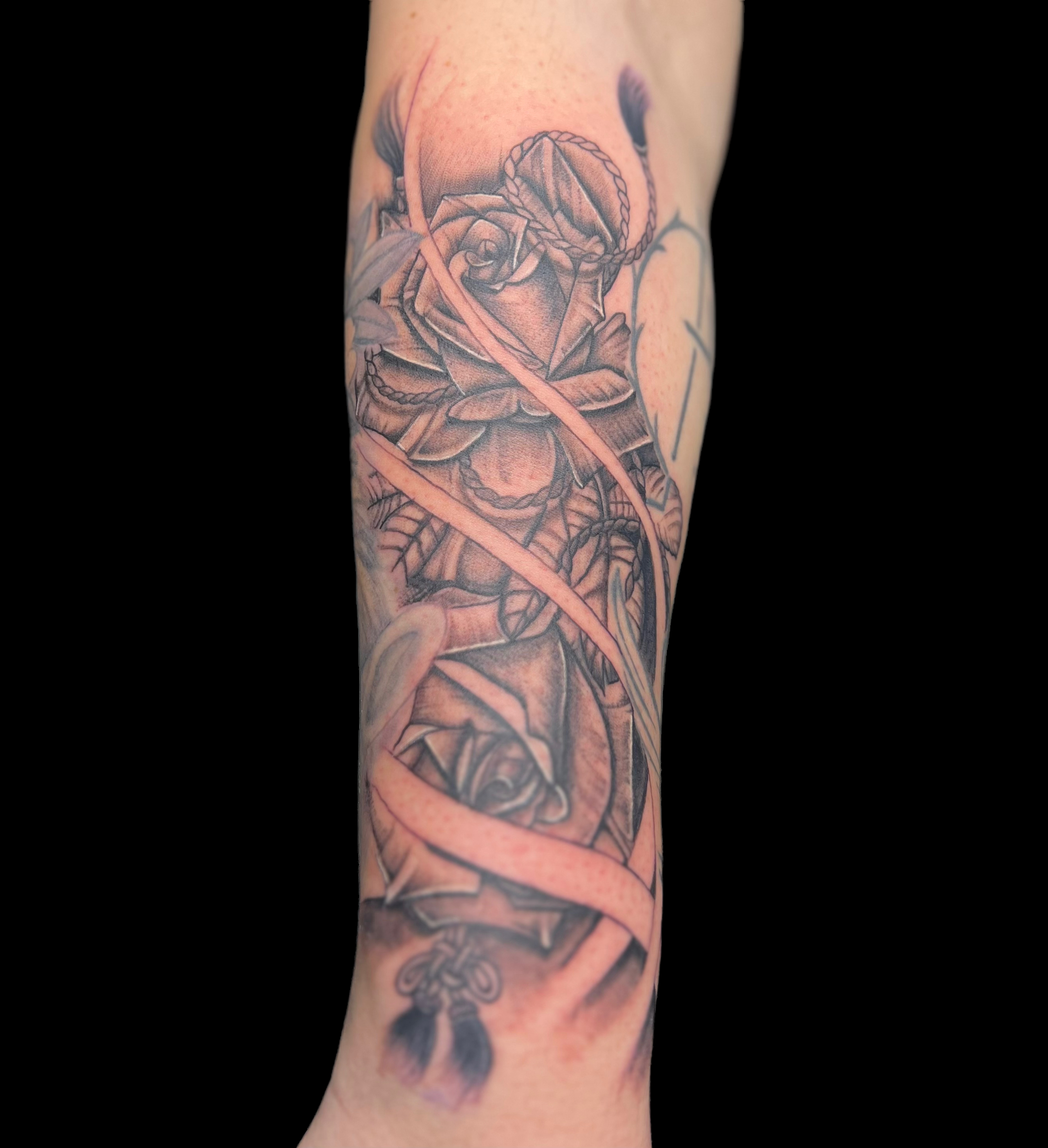 Black and grey illustrative tattoo of roses and rope, forearm