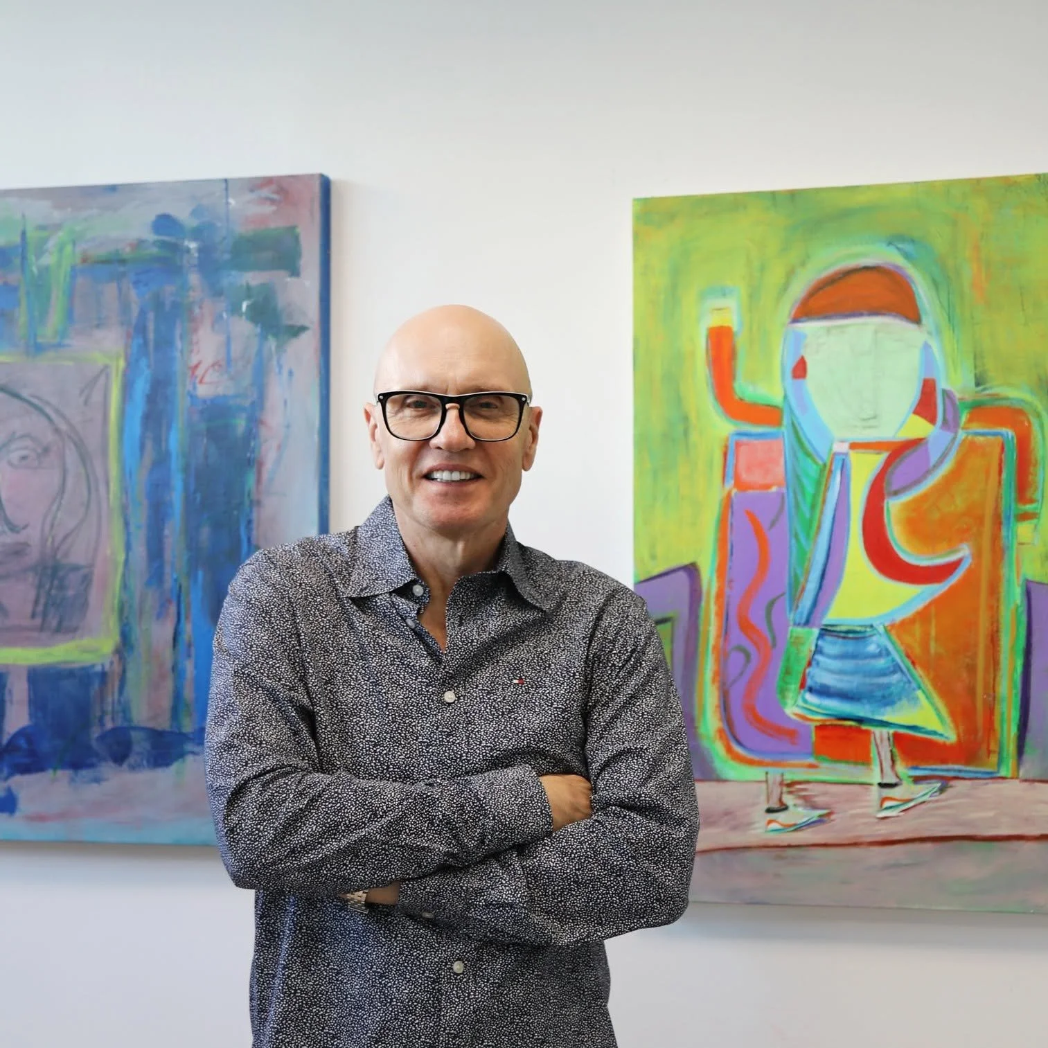 Artist James Kenton Pierce standing in front of two of his paintings.