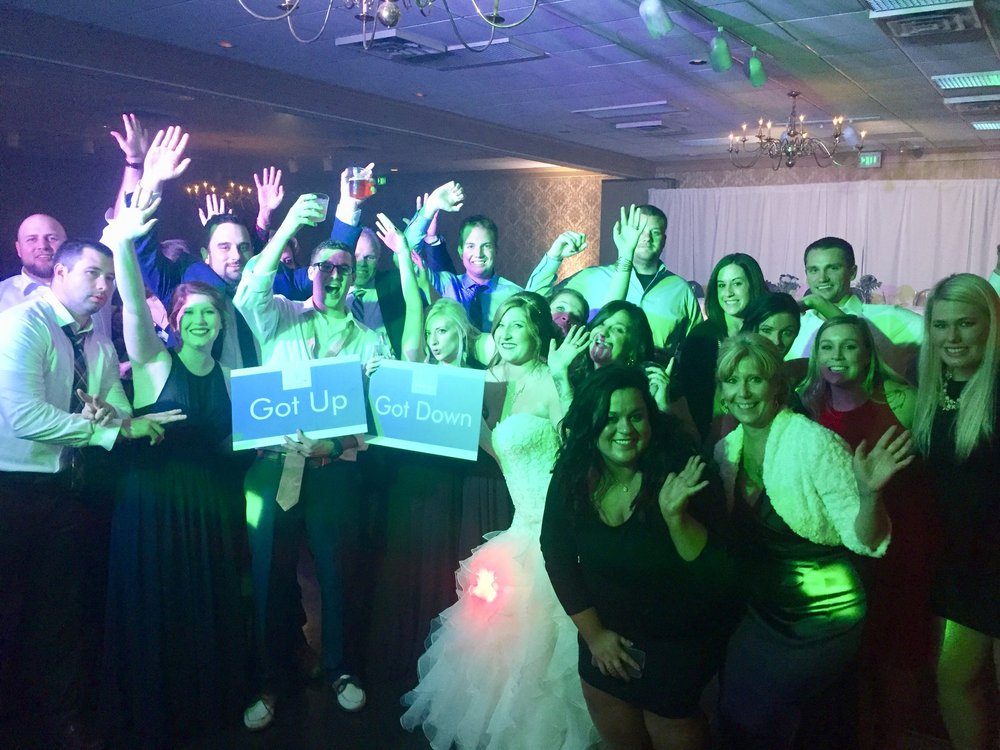 A wedding celebration with guests raising their hands around the couple