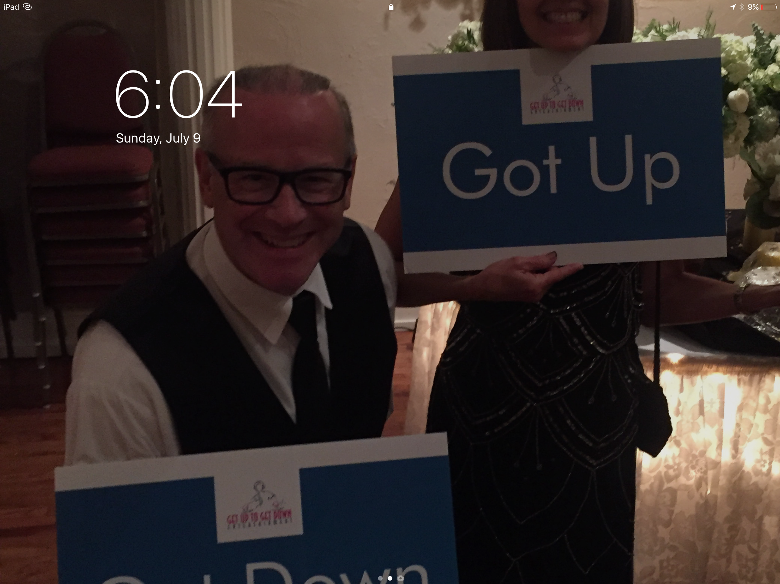Tablet lock screen showing two guests holding Got Up and Got Down signs.