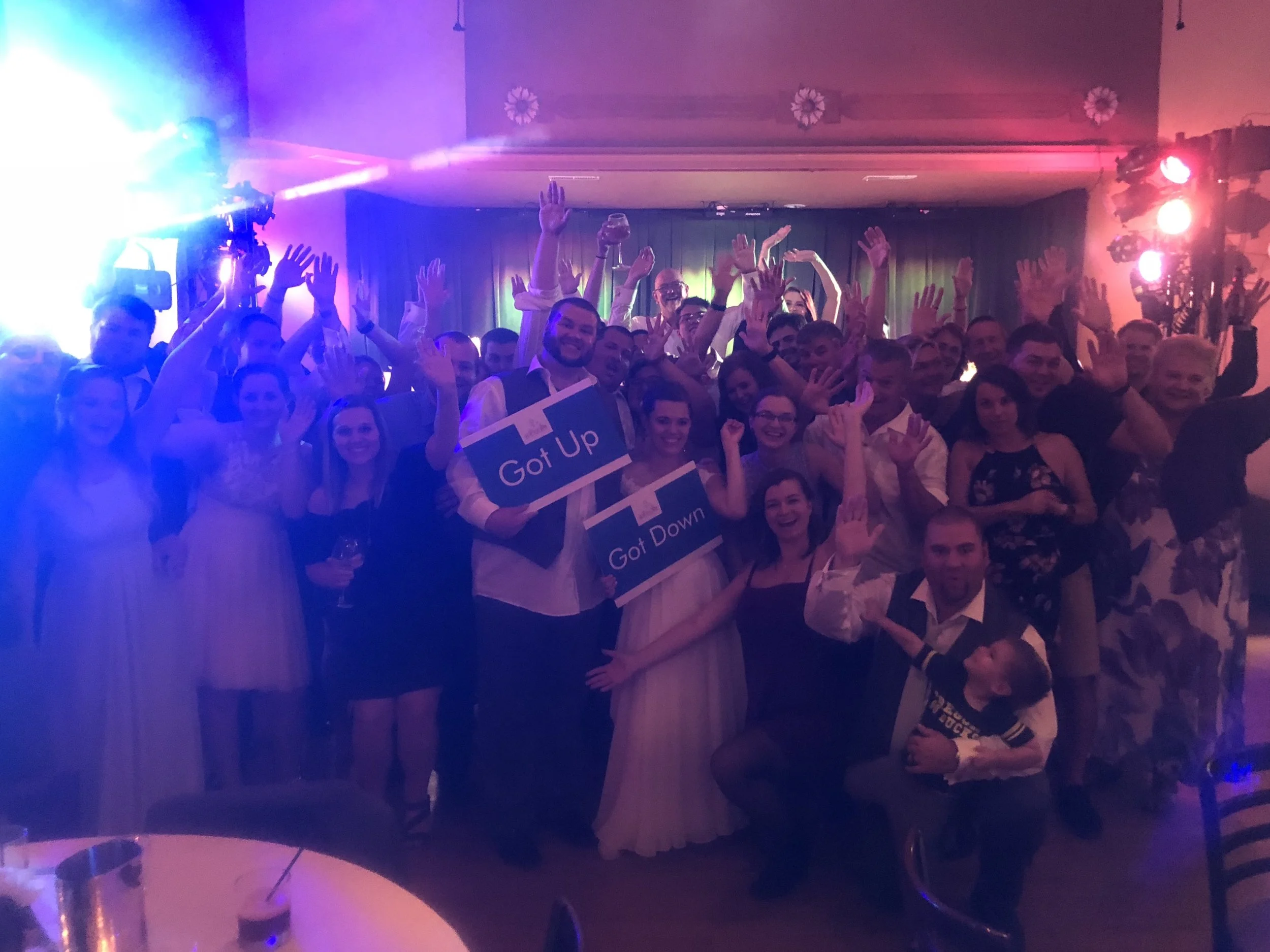 Wedding guests cheering on the dance floor under colorful lights at the Philmore.