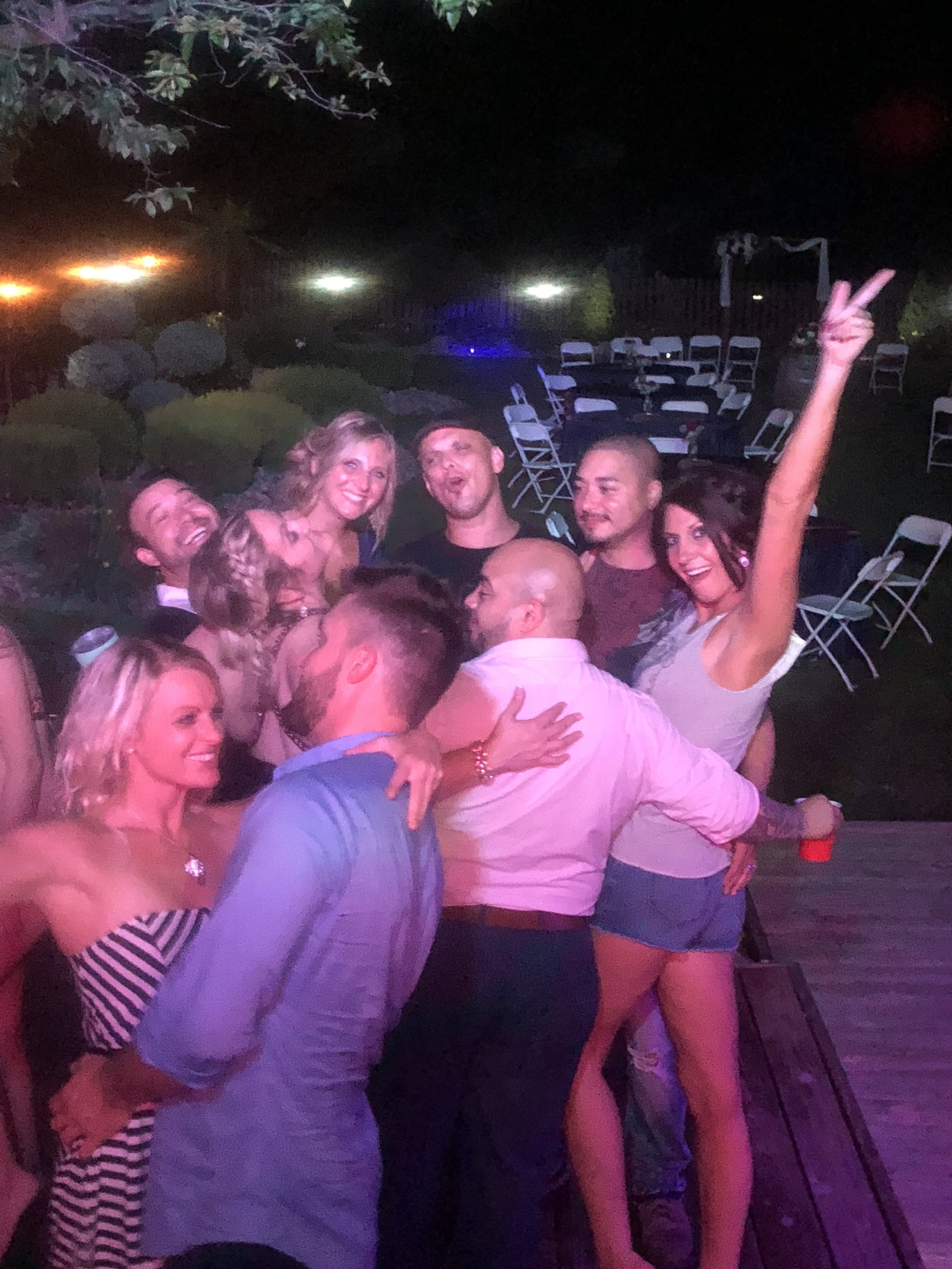 Wedding guests embracing and celebrating together outdoors at night.