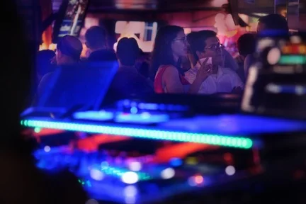 Guests behind a DJ booth with a brightly illuminated turntable in the foreground.