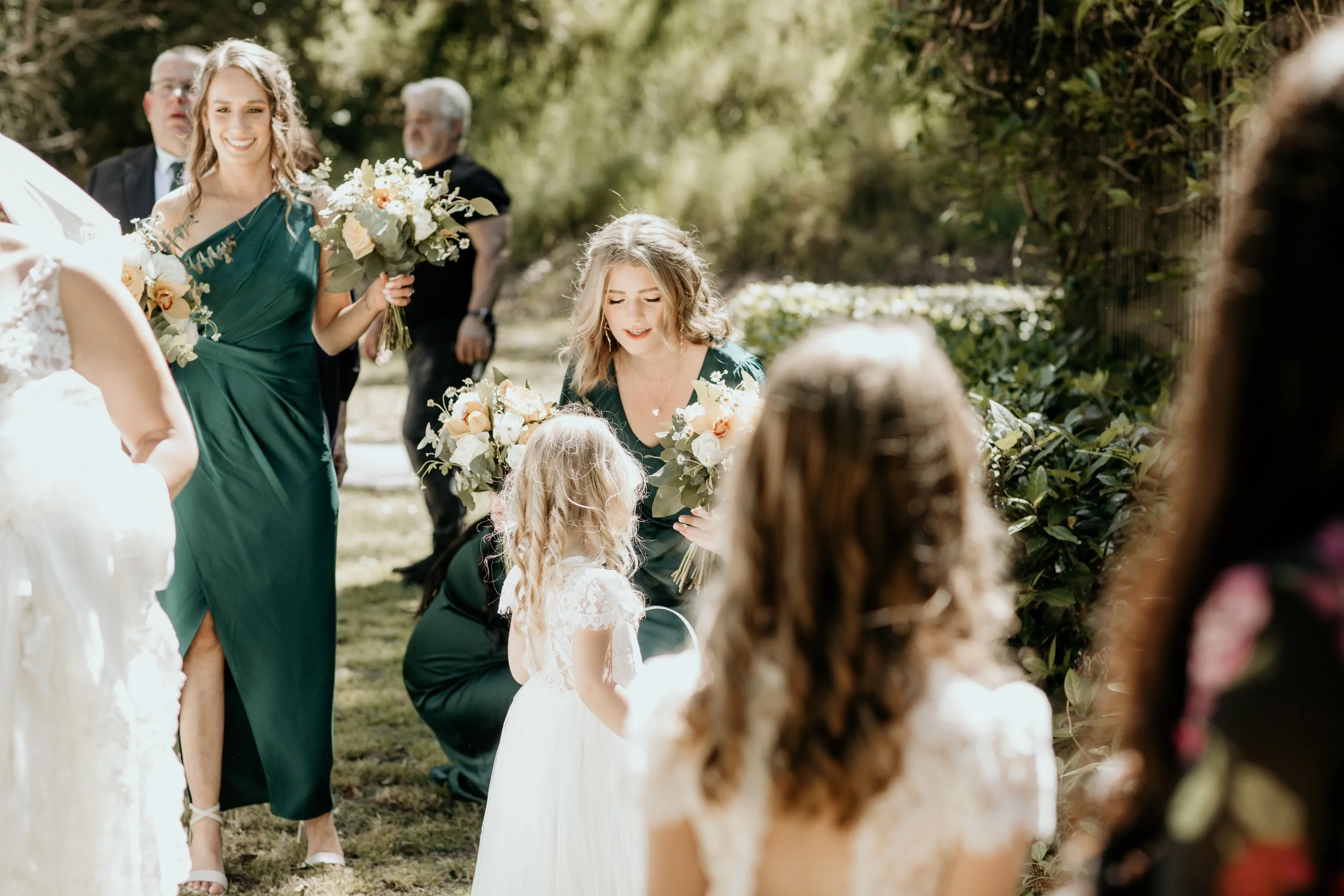 Bridesmaid bending down to greet flowergirls