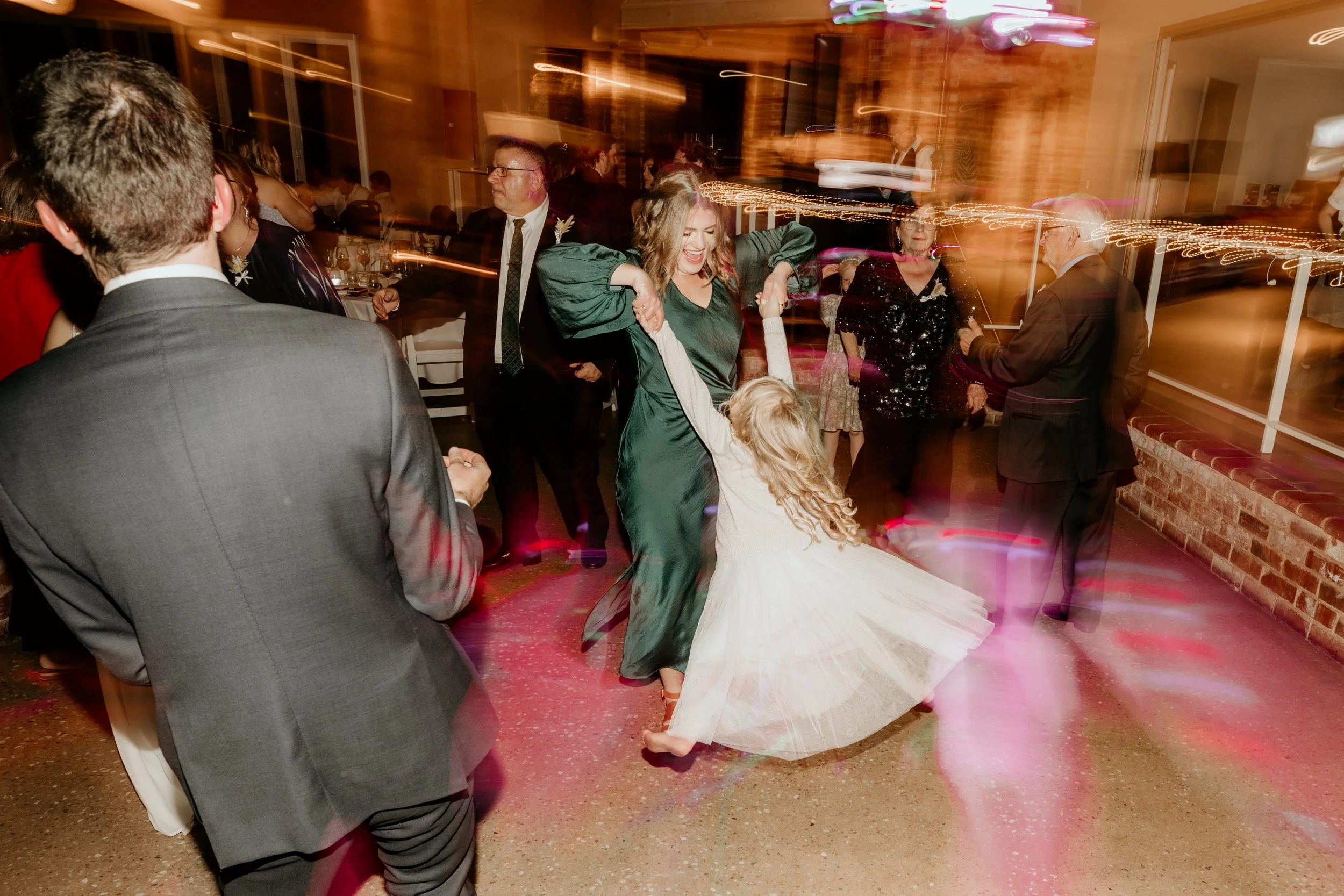 Wedding guest spins young girl at wedding reception