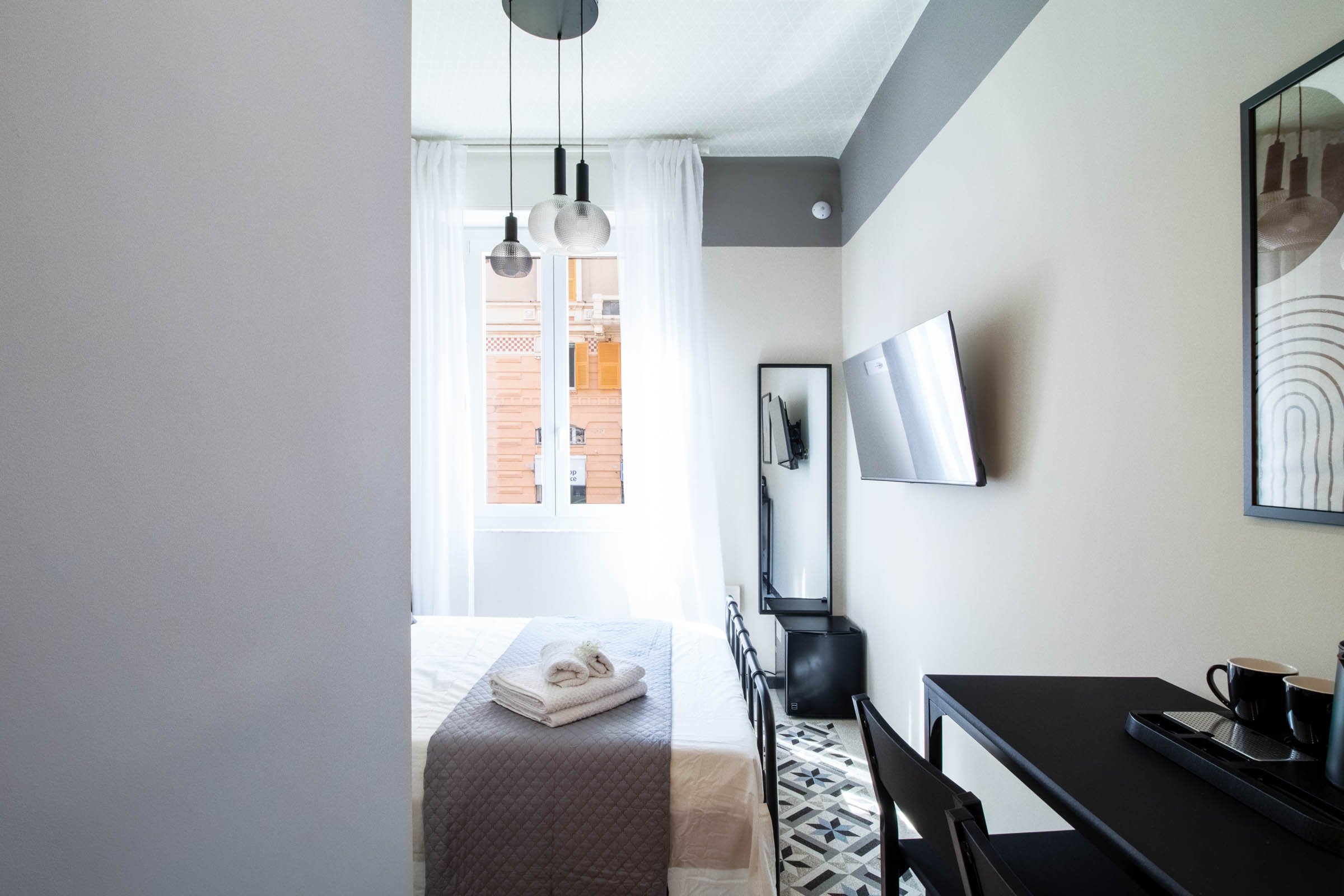Stanza moderna con letto, finestra, TV, lampadari a sfera, pareti di colore grigio e bianco, decorazioni e piante, cucina in stile minimalista.