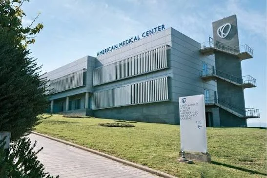 Exterior view of the American Medical Center building with a large sign and a grassy slope.