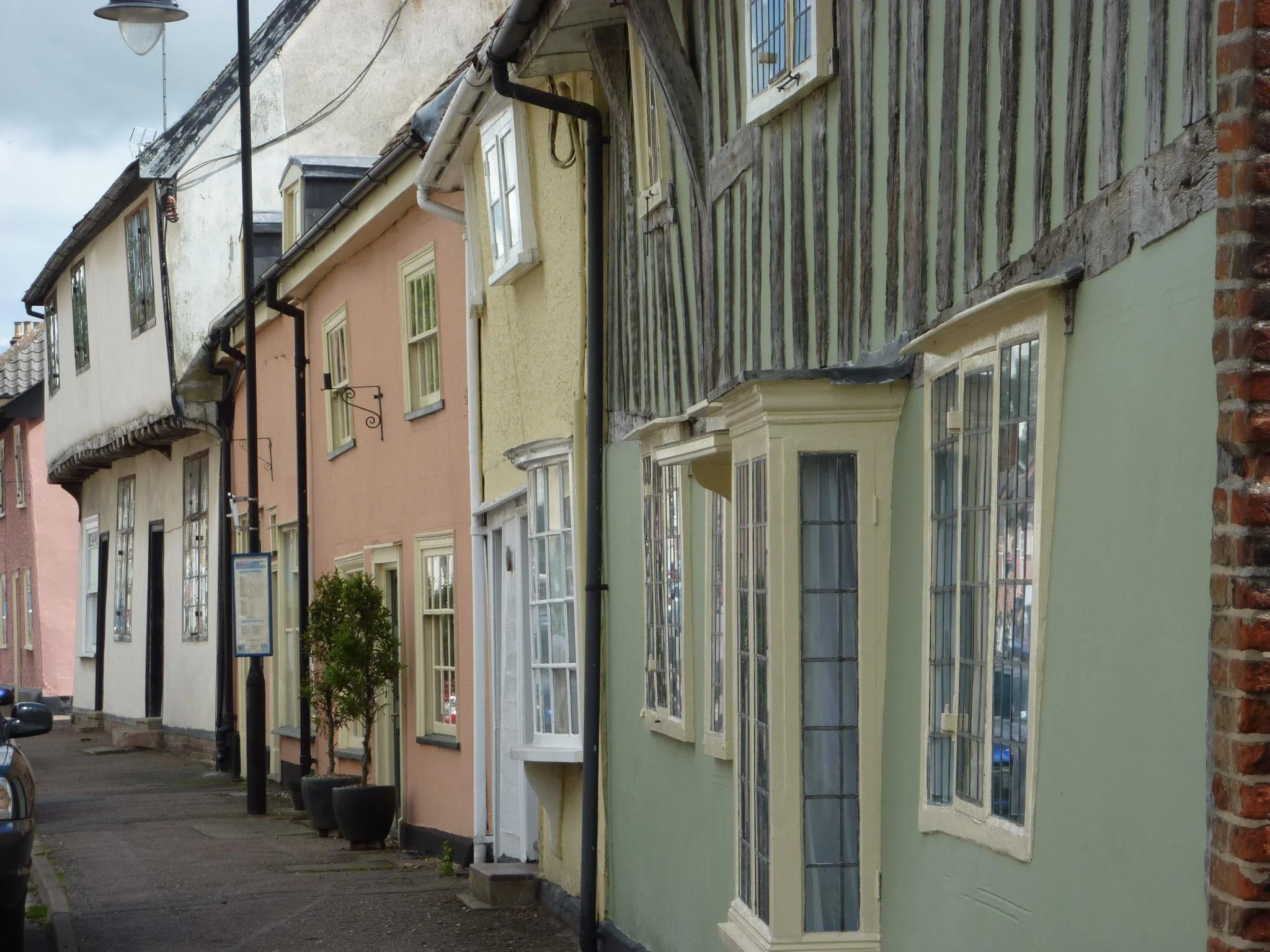 A row of colorful houses with various window styles and a cobblestone street in front, under an overcast sky.