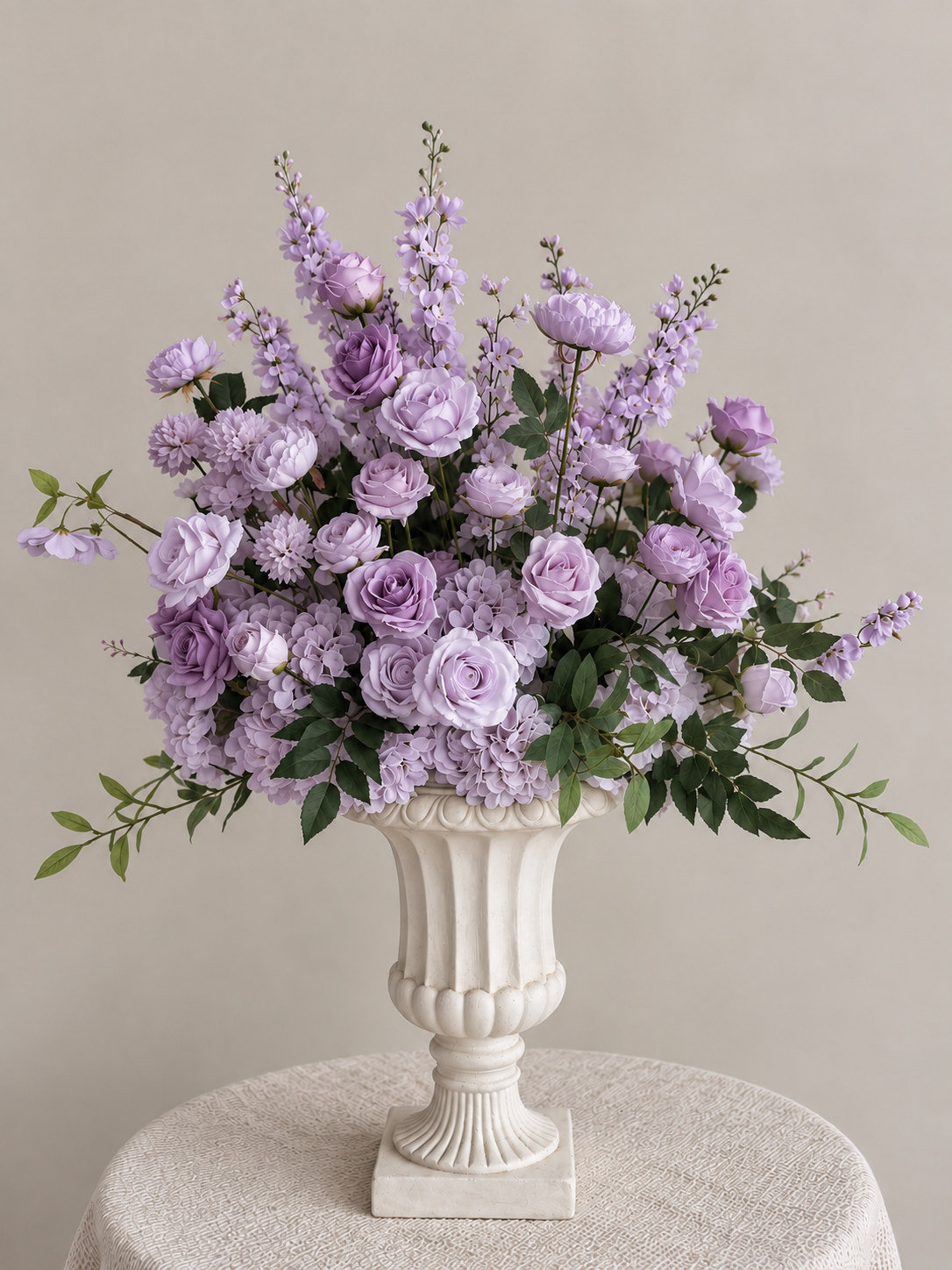 A floral arrangement in a white decorative vase on a textured cream tablecloth with a plain beige background.