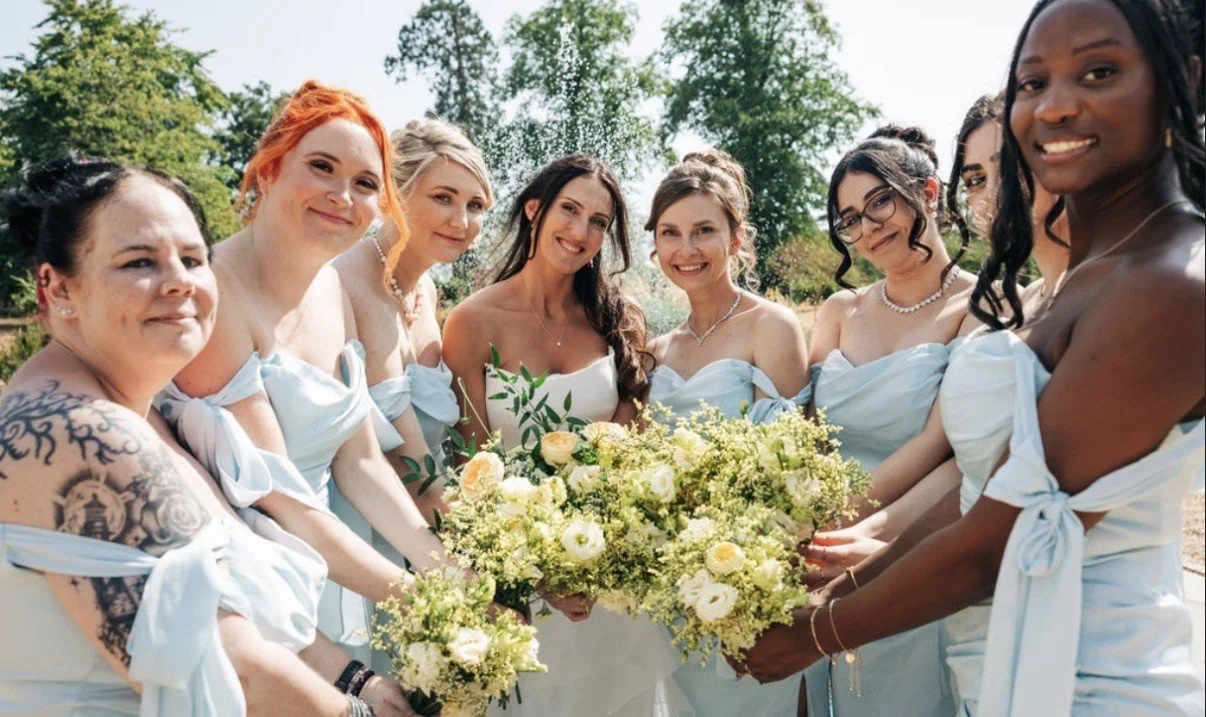 Group of women in white dresses holding bouquets outdoors