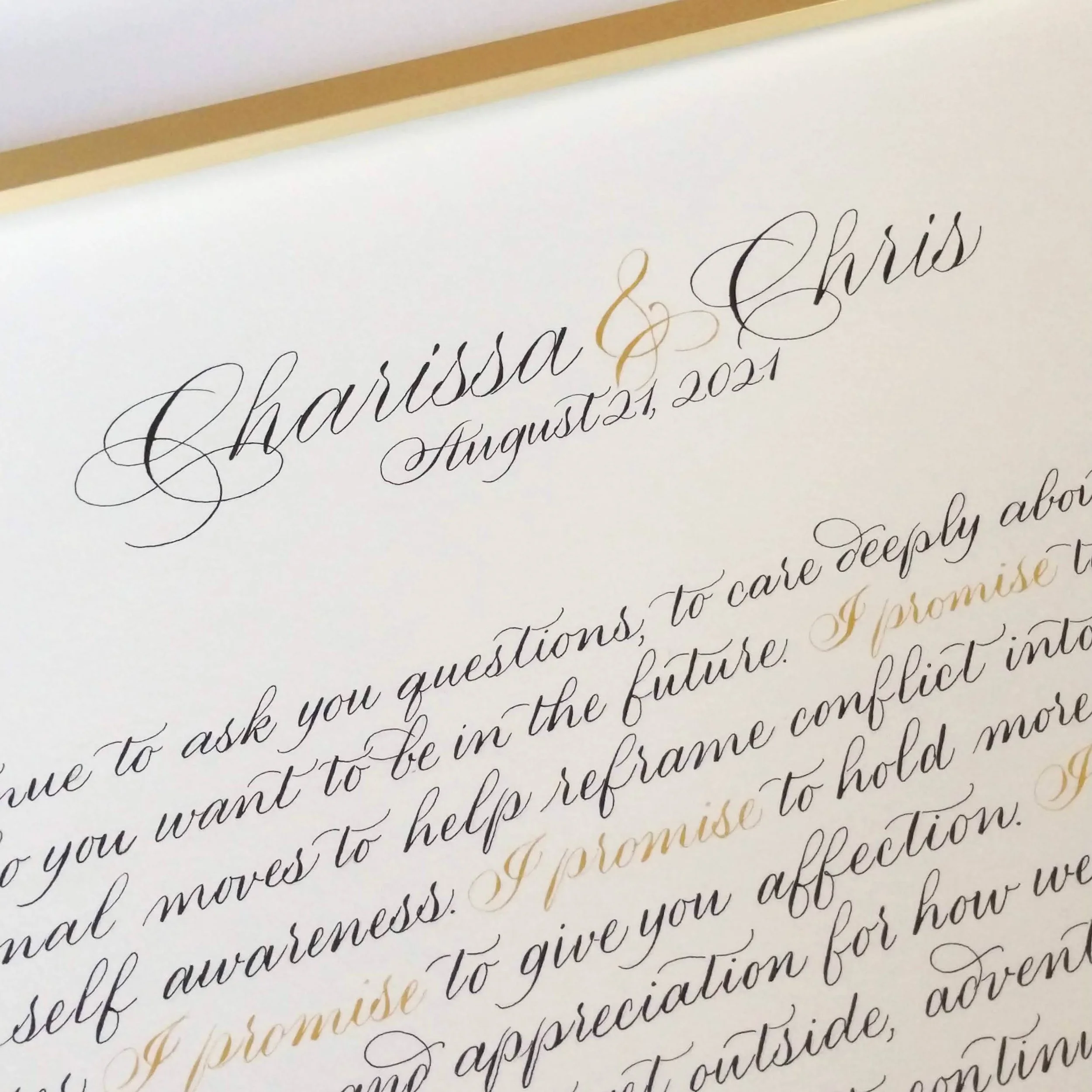 Close-up of a wedding invitation with black and gold calligraphy on cream-colored paper.