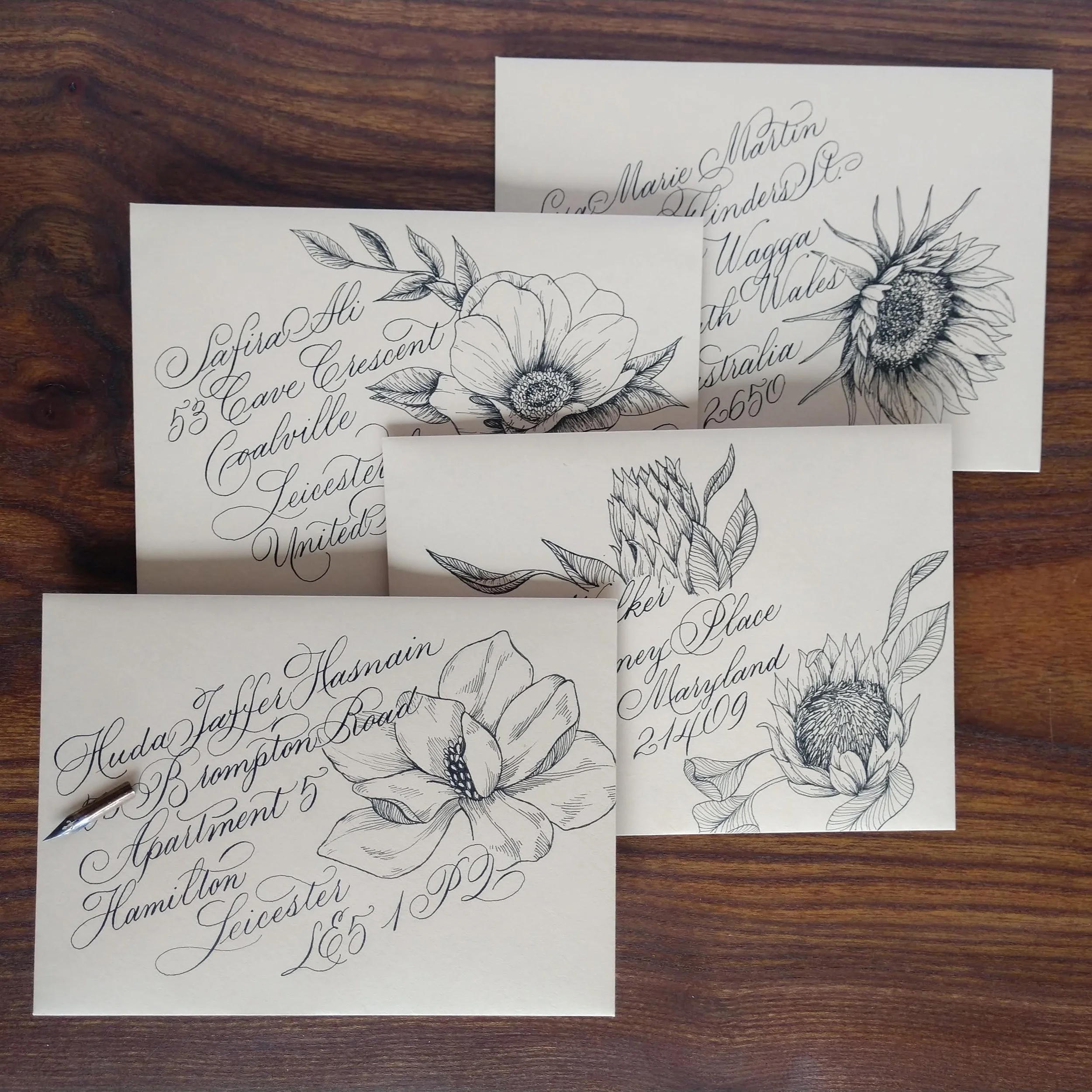 Black and white line drawings of flowers on pieces of paper placed on a wooden surface.