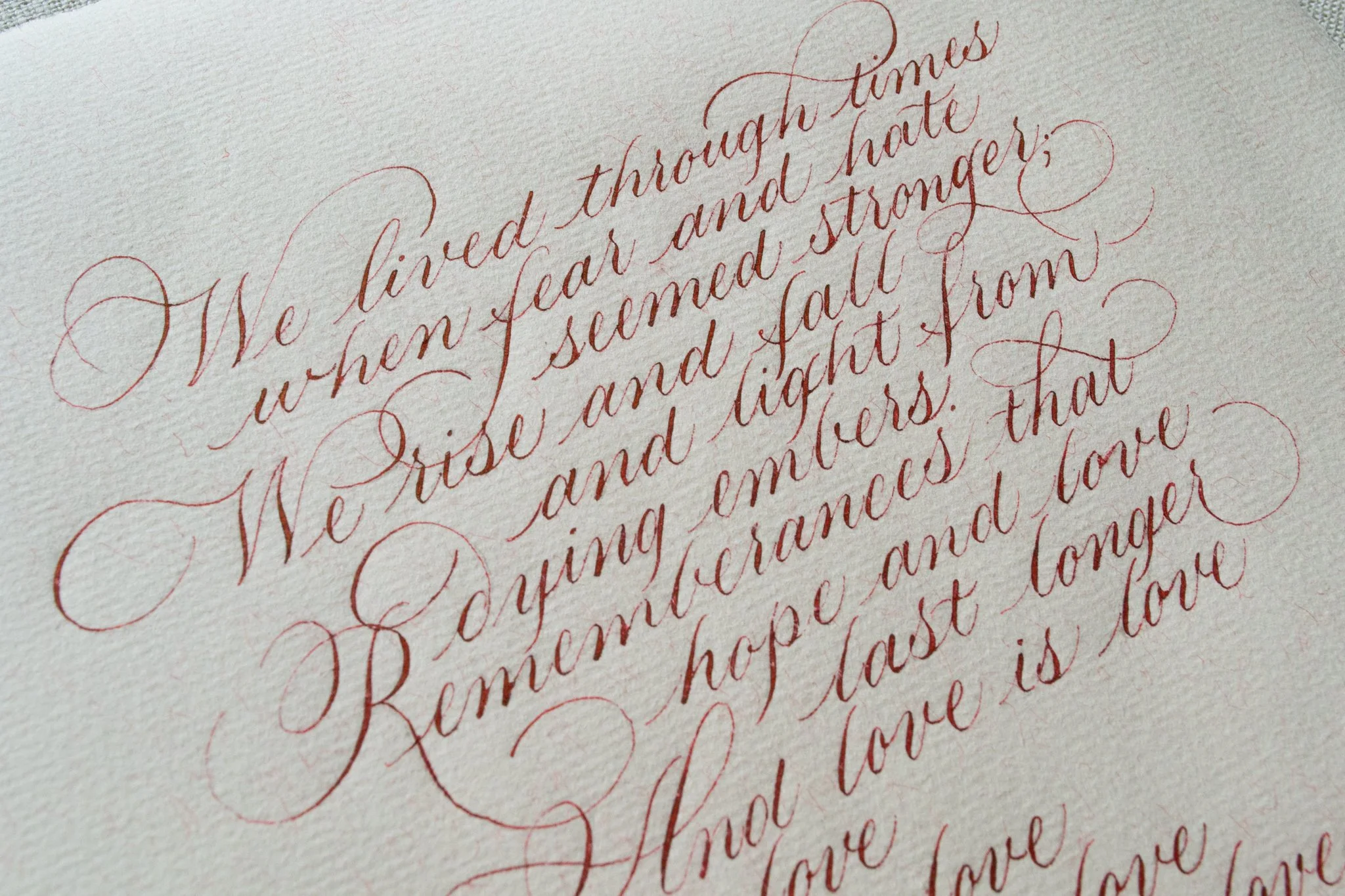 Close-up of cursive handwritten text in red ink on textured paper.