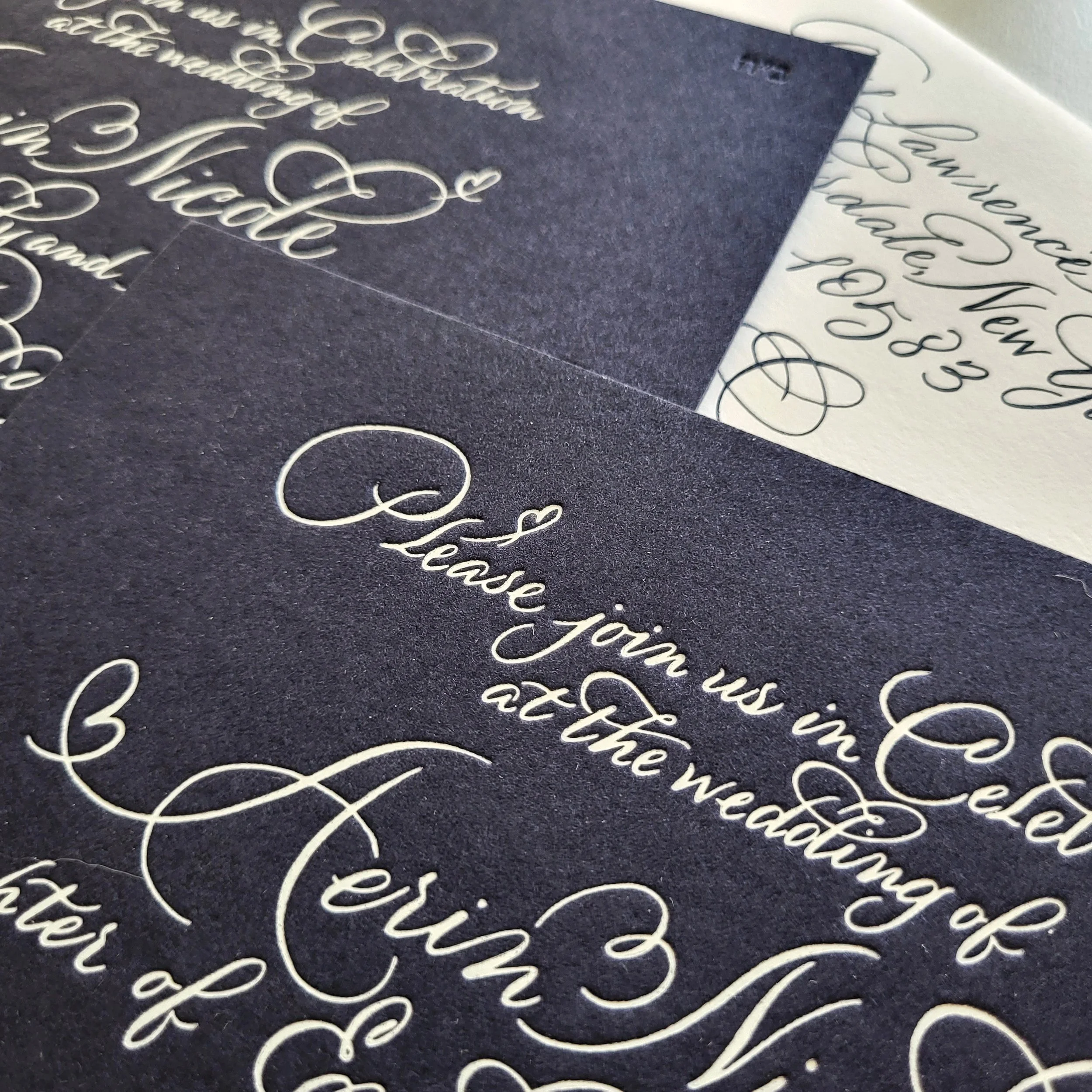 Close-up of a handwritten script on black and white paper with decorative flourishes.