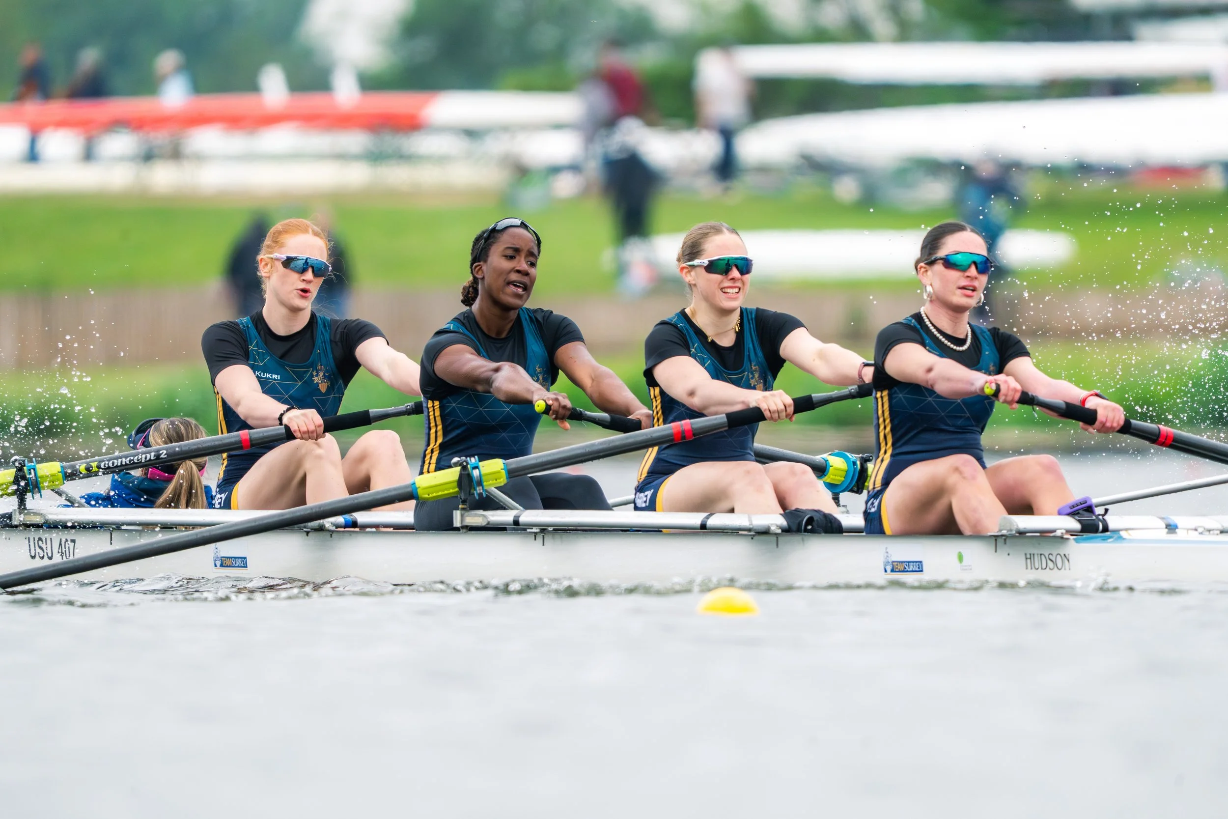 Four women in a rowing boat participating in a race on a body of water.