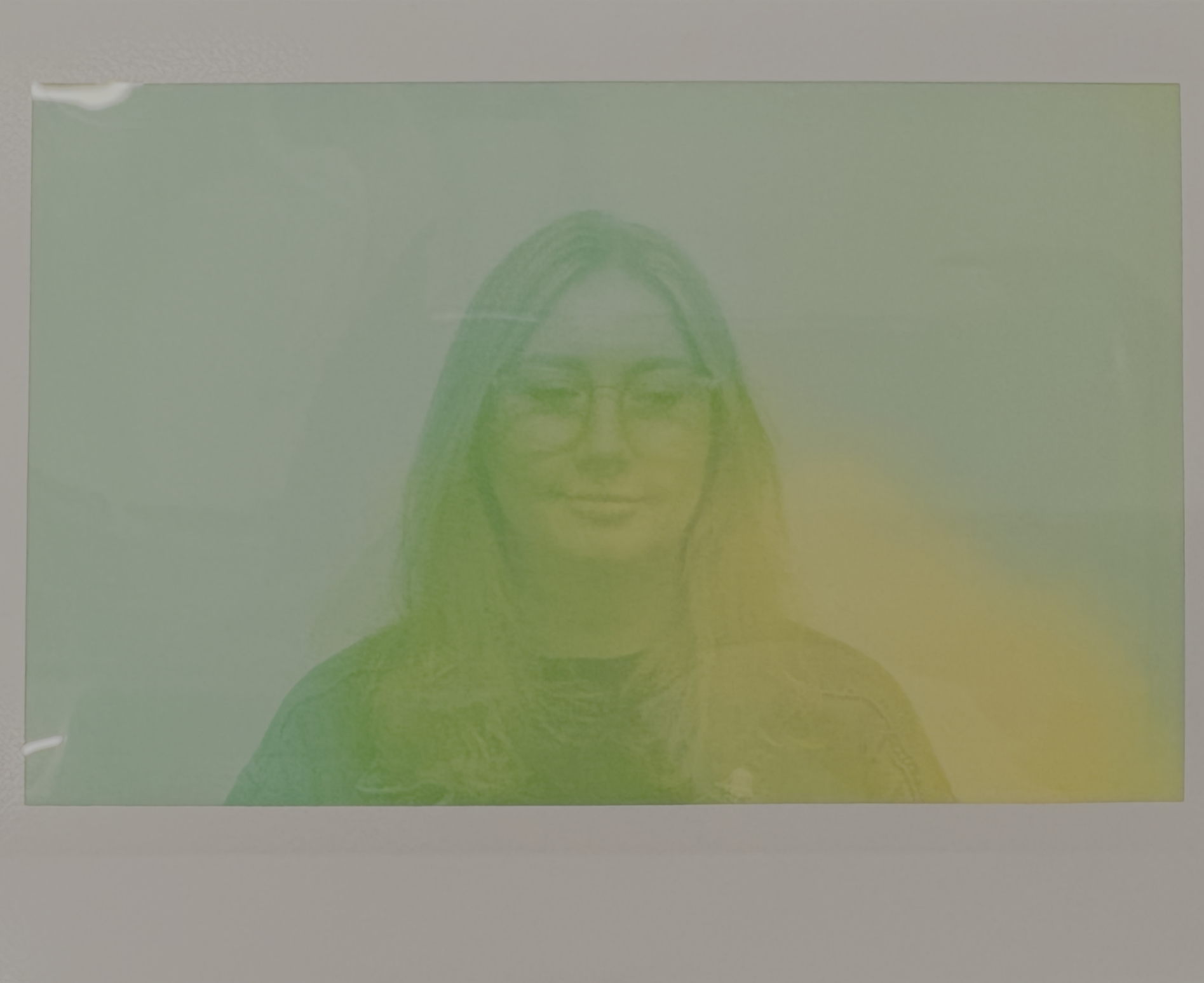 Front of a green and white box with a faint, tilted illustration of a woman's face with dark hair and glasses.