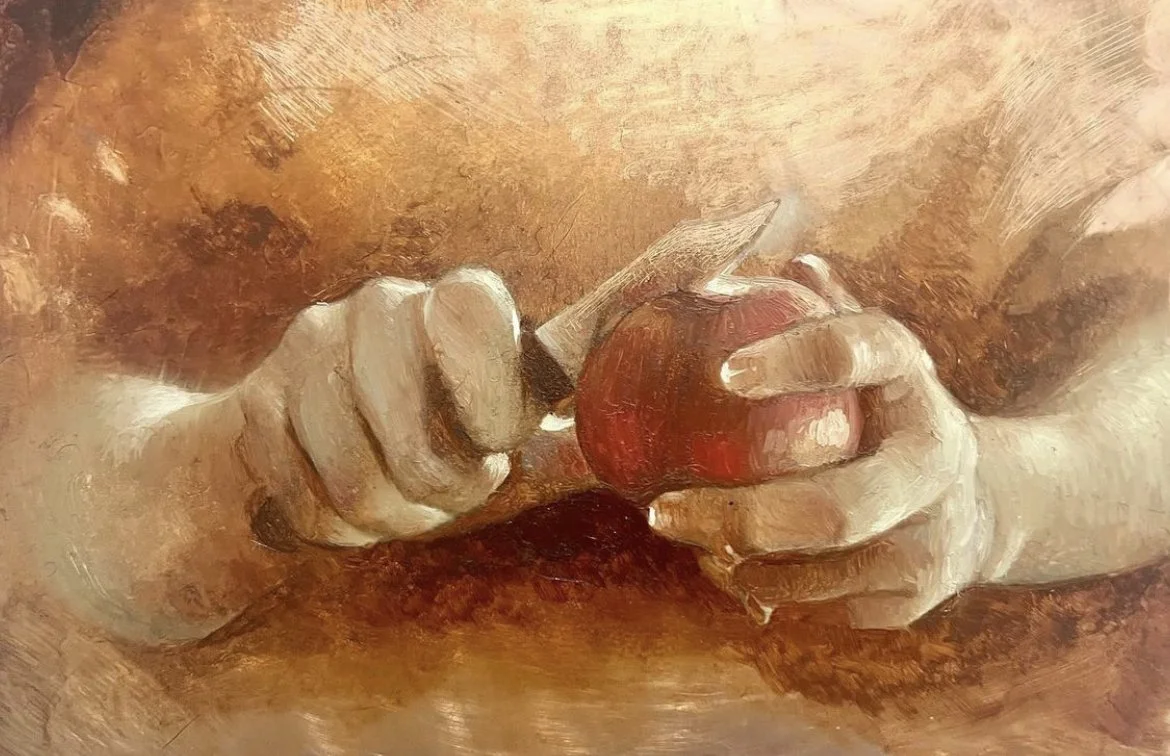 Close-up of a person's hands, with one holding a red apple and the other using a knife to cut it.