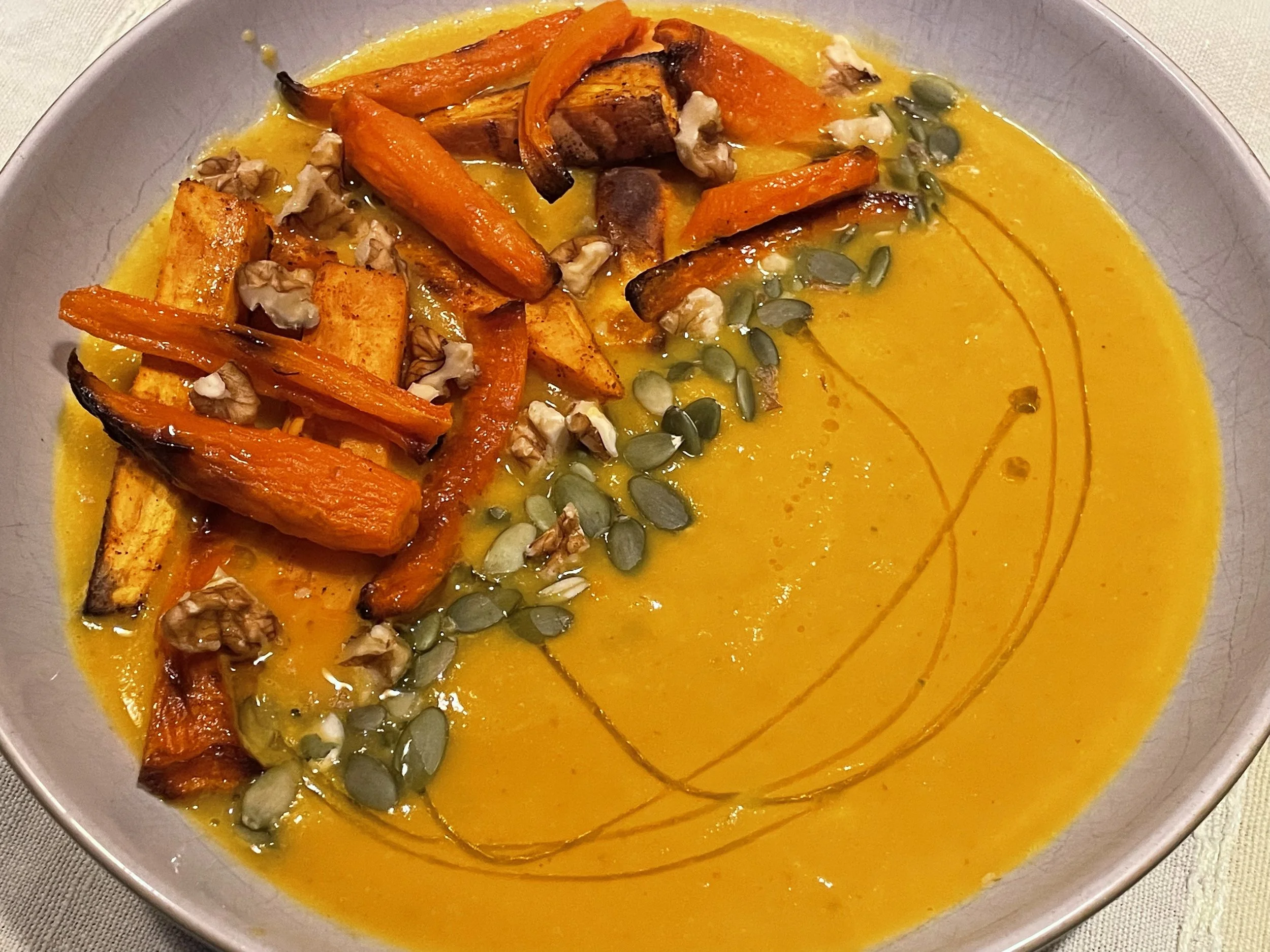 Carrout soup garnished with carrots, pumpkin seeds and sweet potato