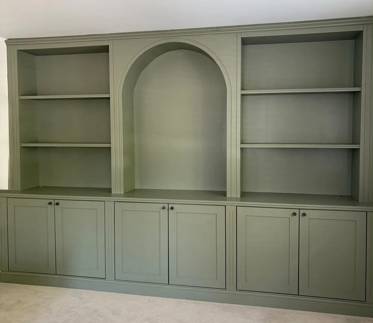 Empty green built-in bookshelf with shelves and cabinets