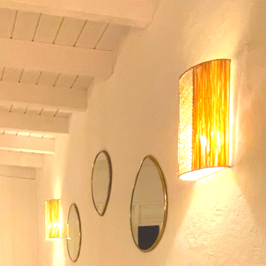 Estructura de pared decorativa con espejos redondos y lámparas de pared con pantallas anaranjadas