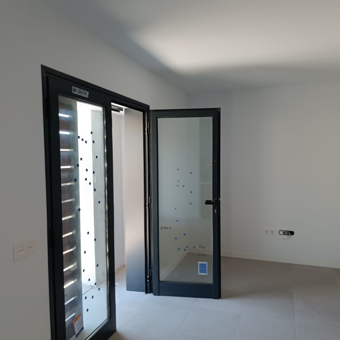 Ventana y puerta de vidrio con marco negro en una pared blanca del interior de una casa