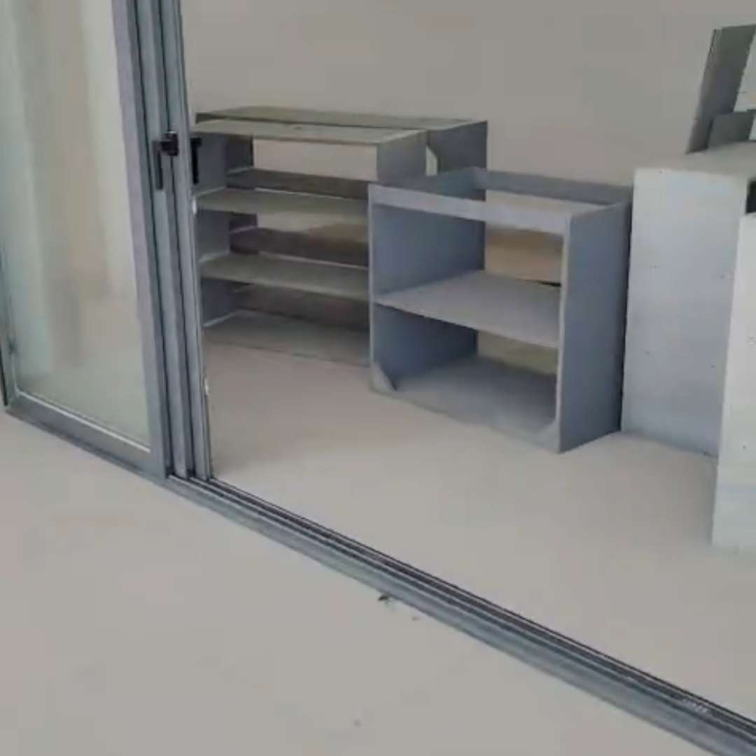 Estanterías de madera en una habitación junto a un marco de puerta corrediza de vidrio.
