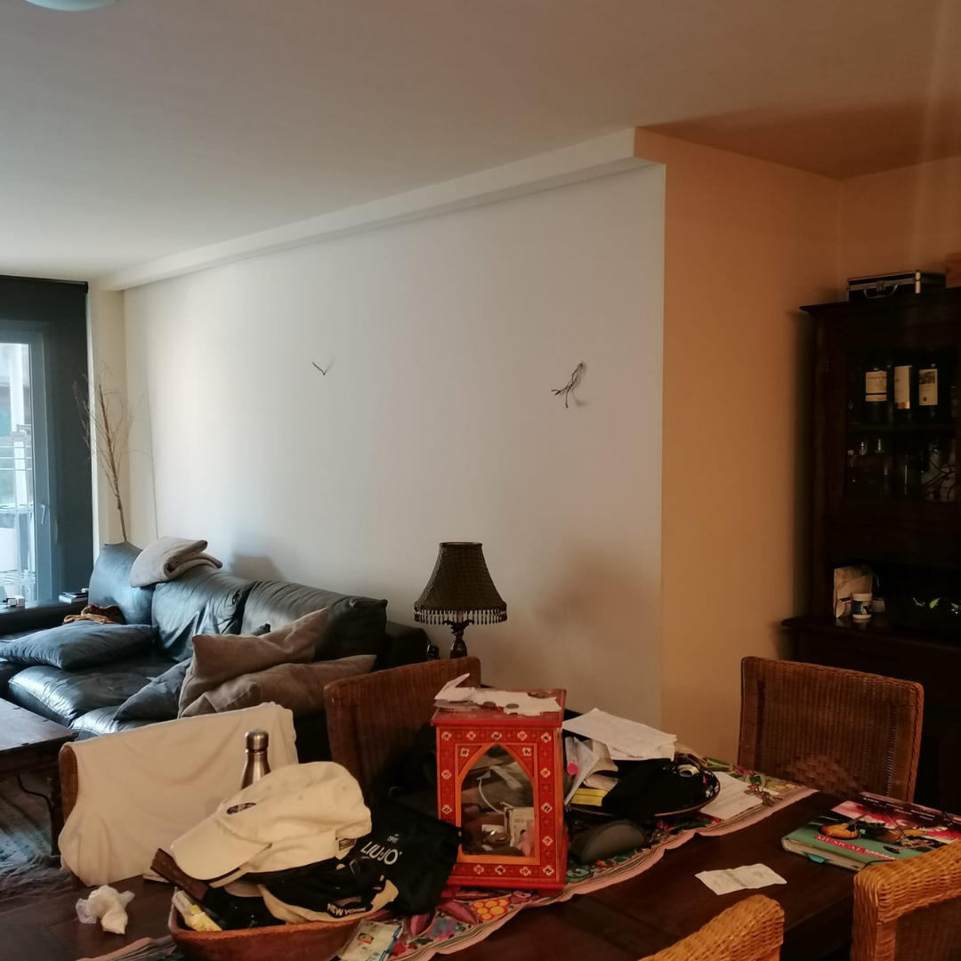 Sala de estar y comedor desordenados con muebles y objetos dispersos.