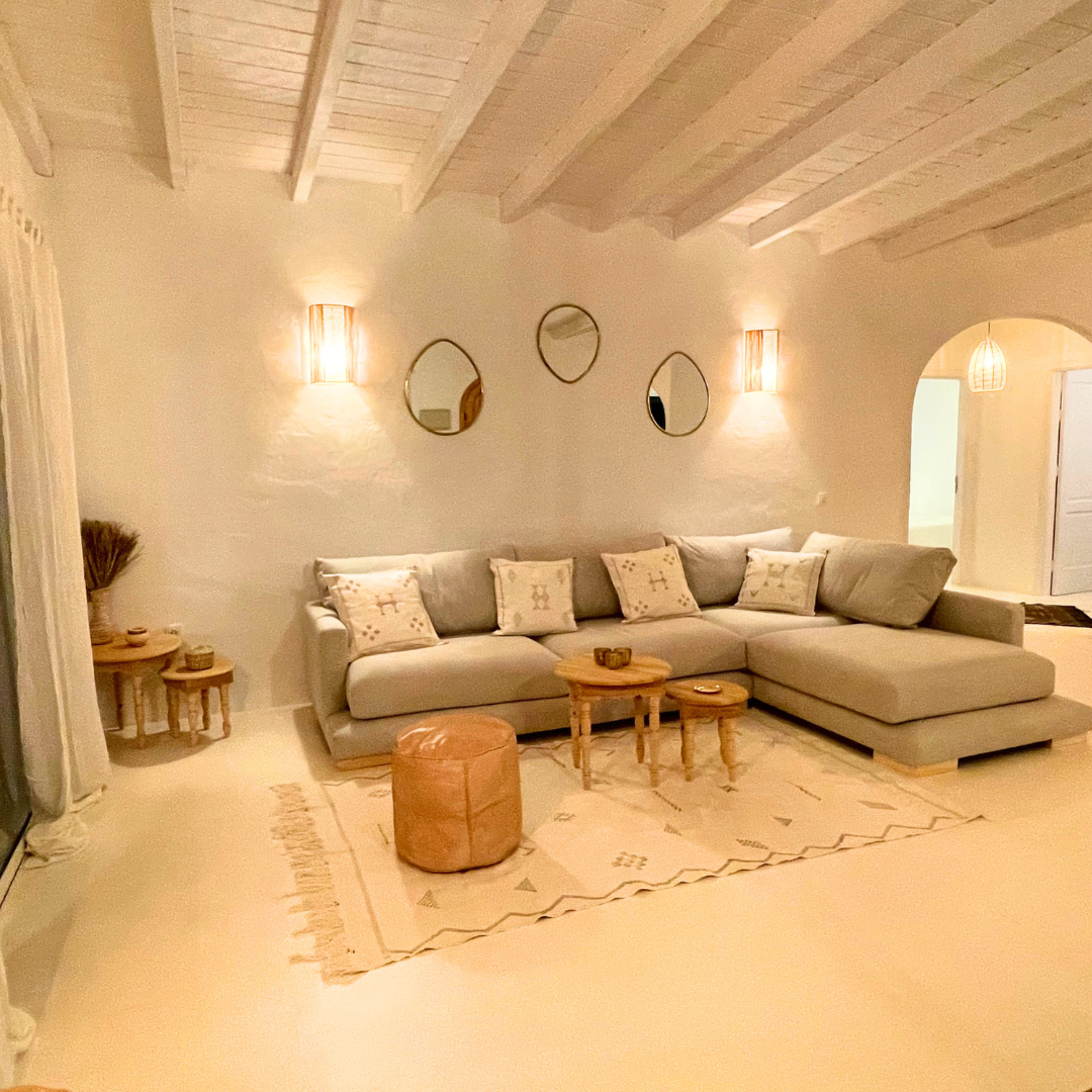 Sala de estar con sofá gris, cojines decorativos, mesa de centro de madera y espejo en la pared.