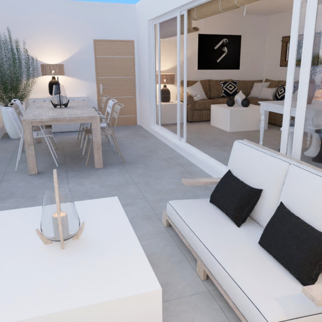 Espacio de interior con muebles blancos y decorativos en tonos neutros, incluyendo una mesa de comedor, sillones, lámparas y jarrones, con una pared de vidrio que separa dos áreas.