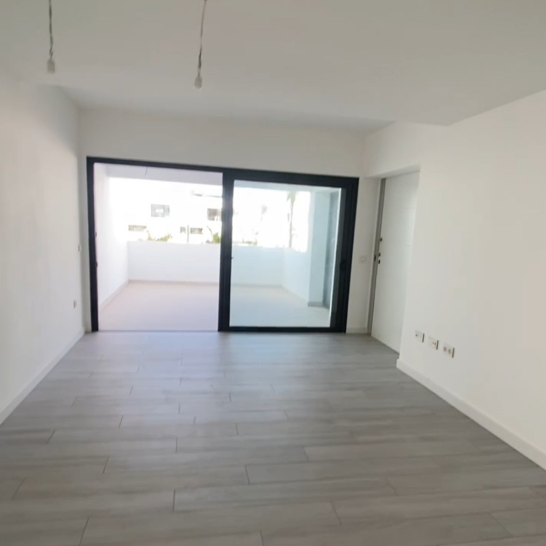 Sala vacía con ventanas grandes y piso de madera clara.