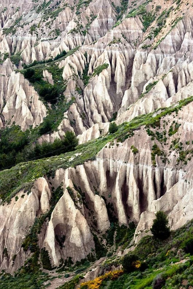 Paesaggio con formazione rocciosa naturale, con rocce a formazioni verticali e vegetazione sparse.