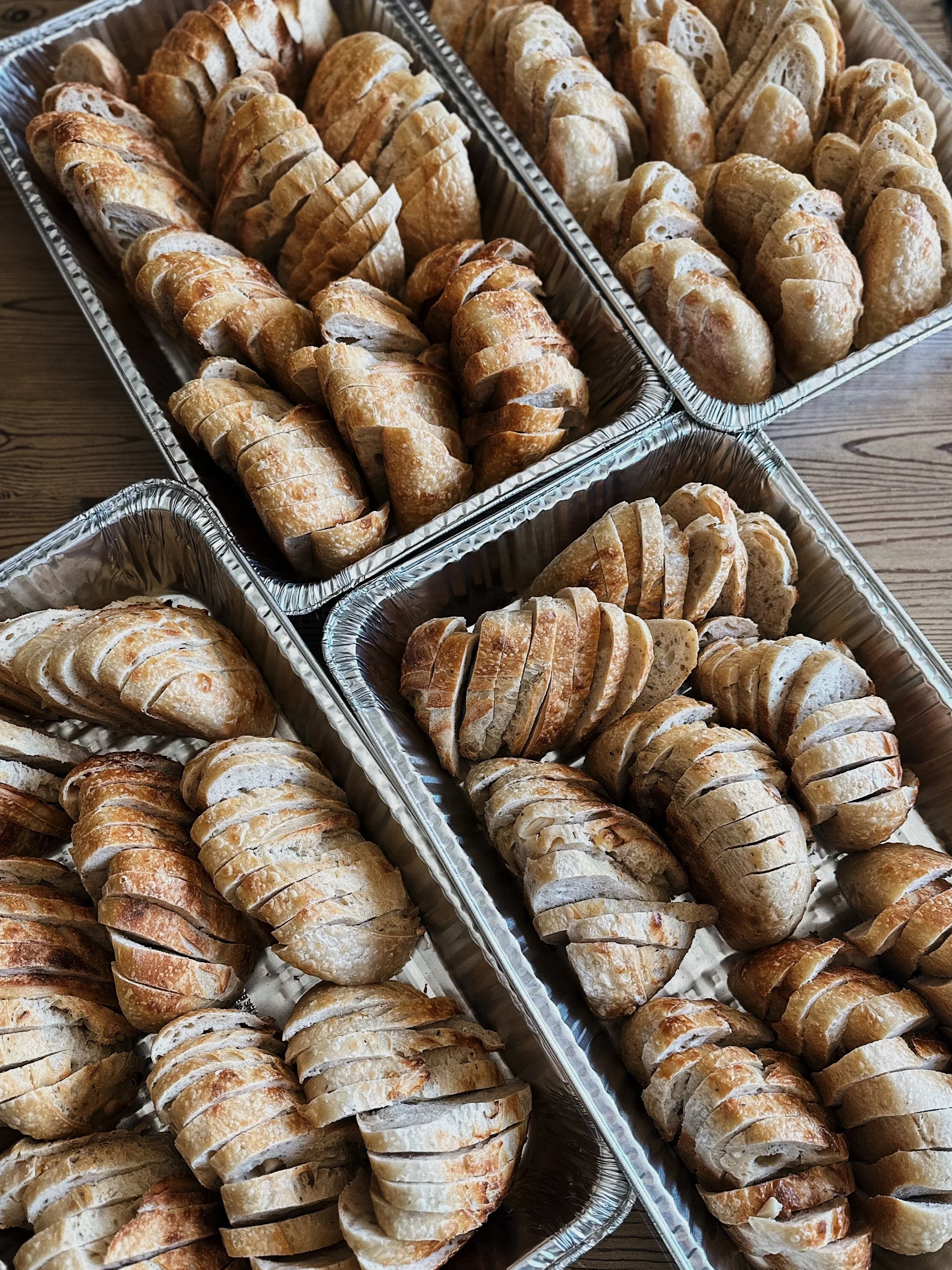 Aluminum trays filled with sliced sourdough bread.
